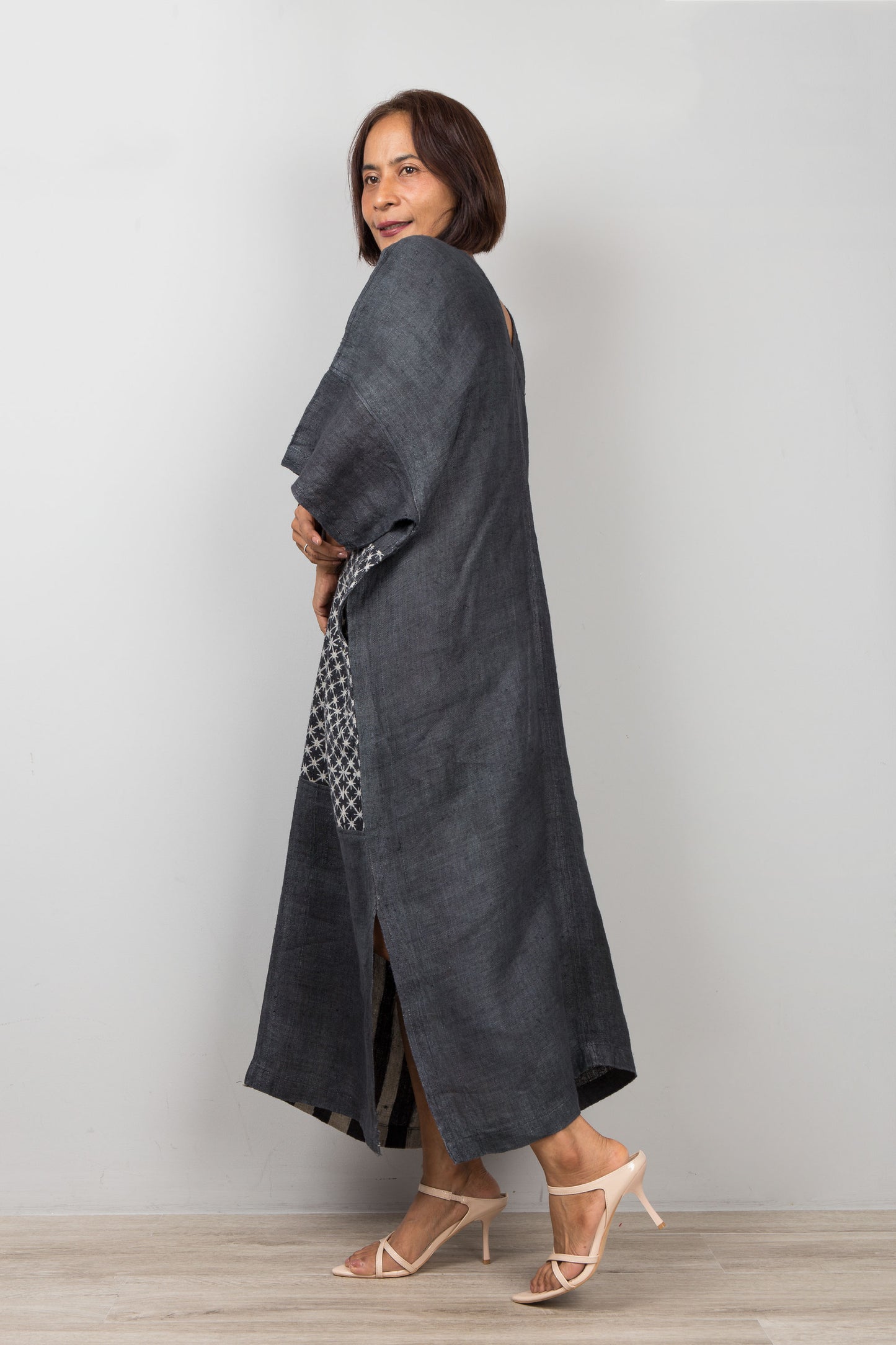 Woman wearing a long dark gray dress against a plain background