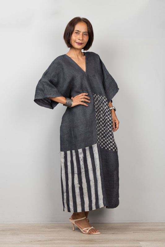 Woman wearing a petite caftan dress in black, made form hemp patchwork