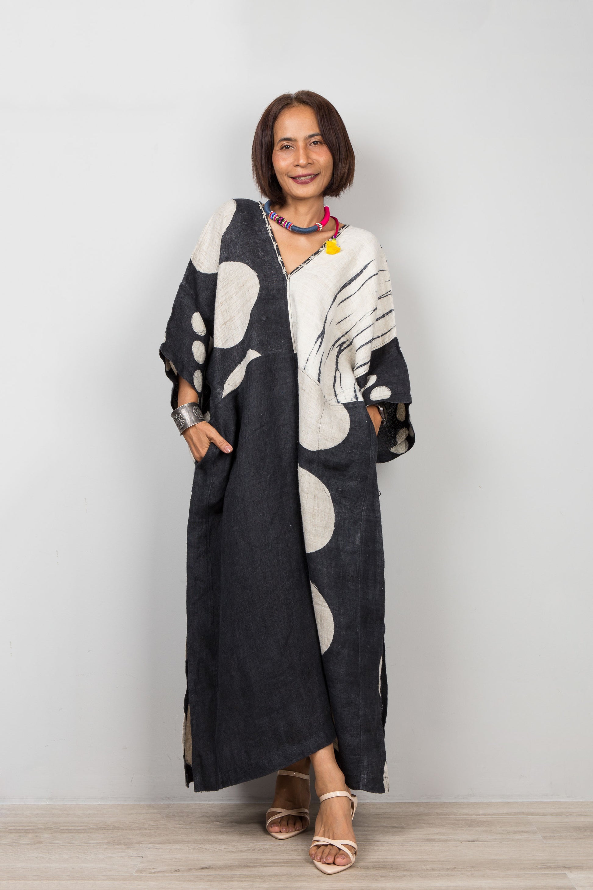Woman wearing a long, black and white hemp kaftan dress against a plain background