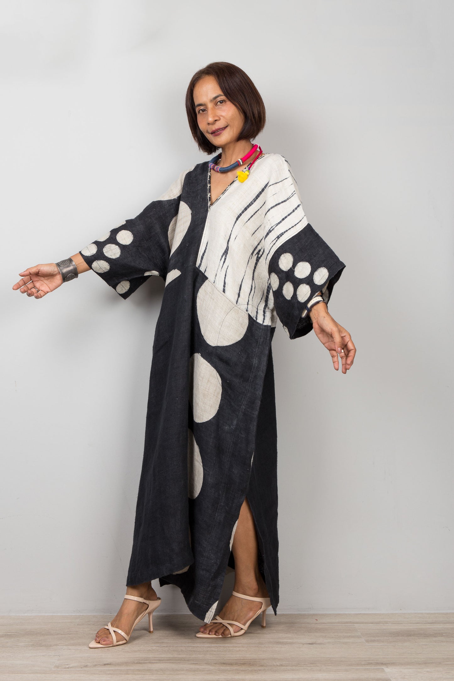 Woman wearing a black and white patterned hemp caftan against a plain background