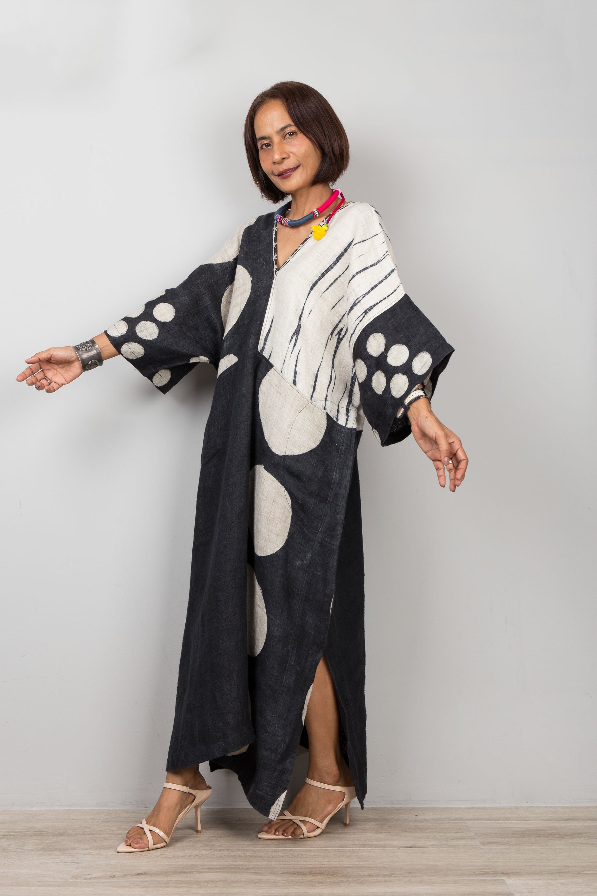 Woman wearing a black and white patterned hemp caftan against a plain background