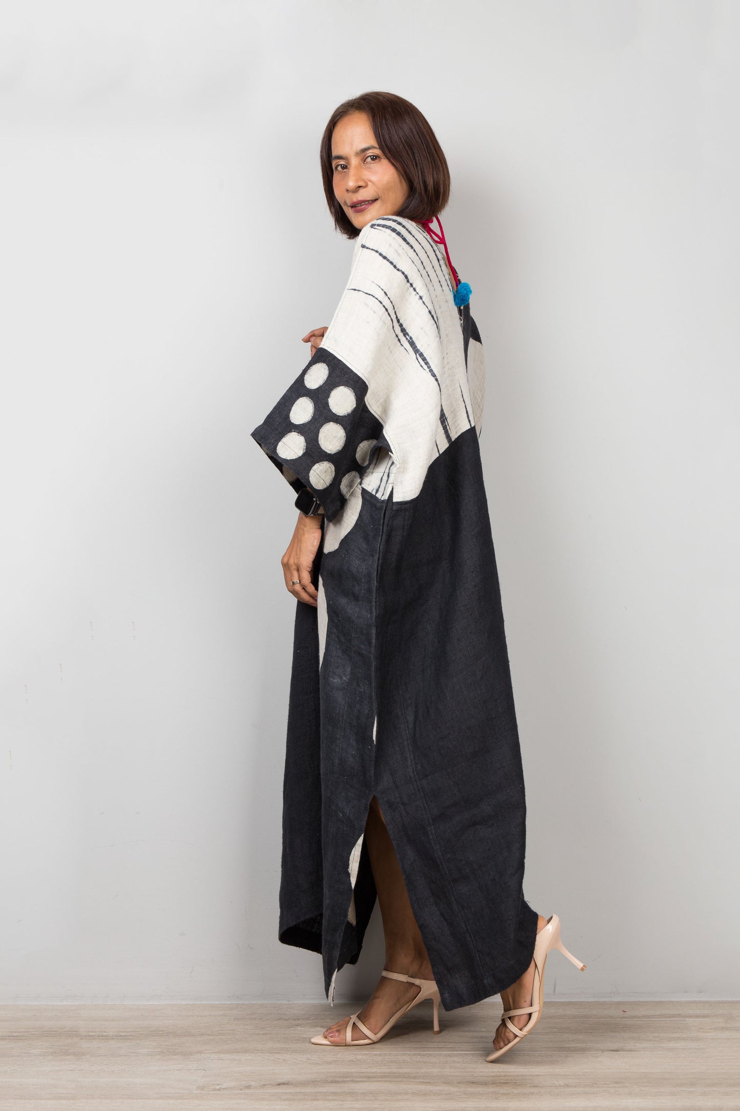 Woman wearing a long black and white patterned caftan dress against a plain background