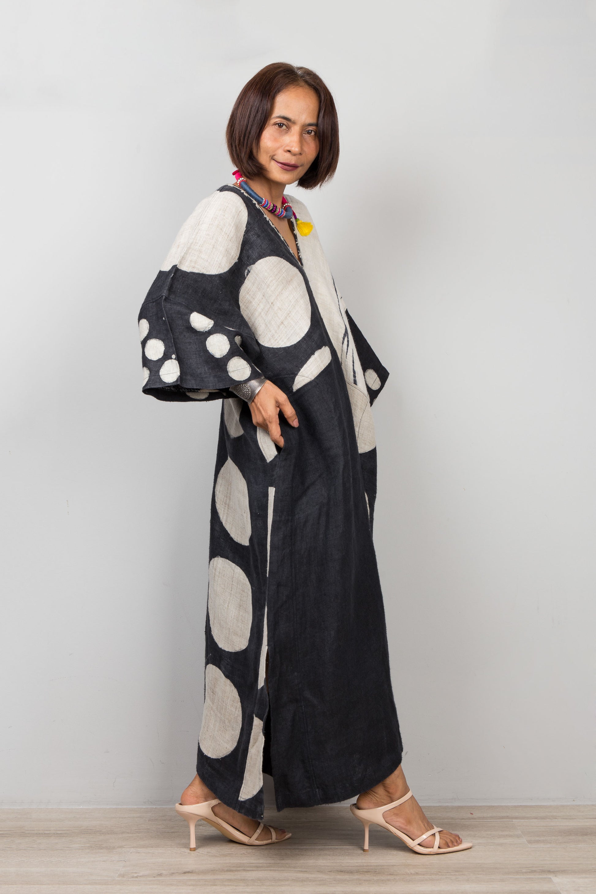 Woman wearing a black and white polka dot kaftan dress against a plain background