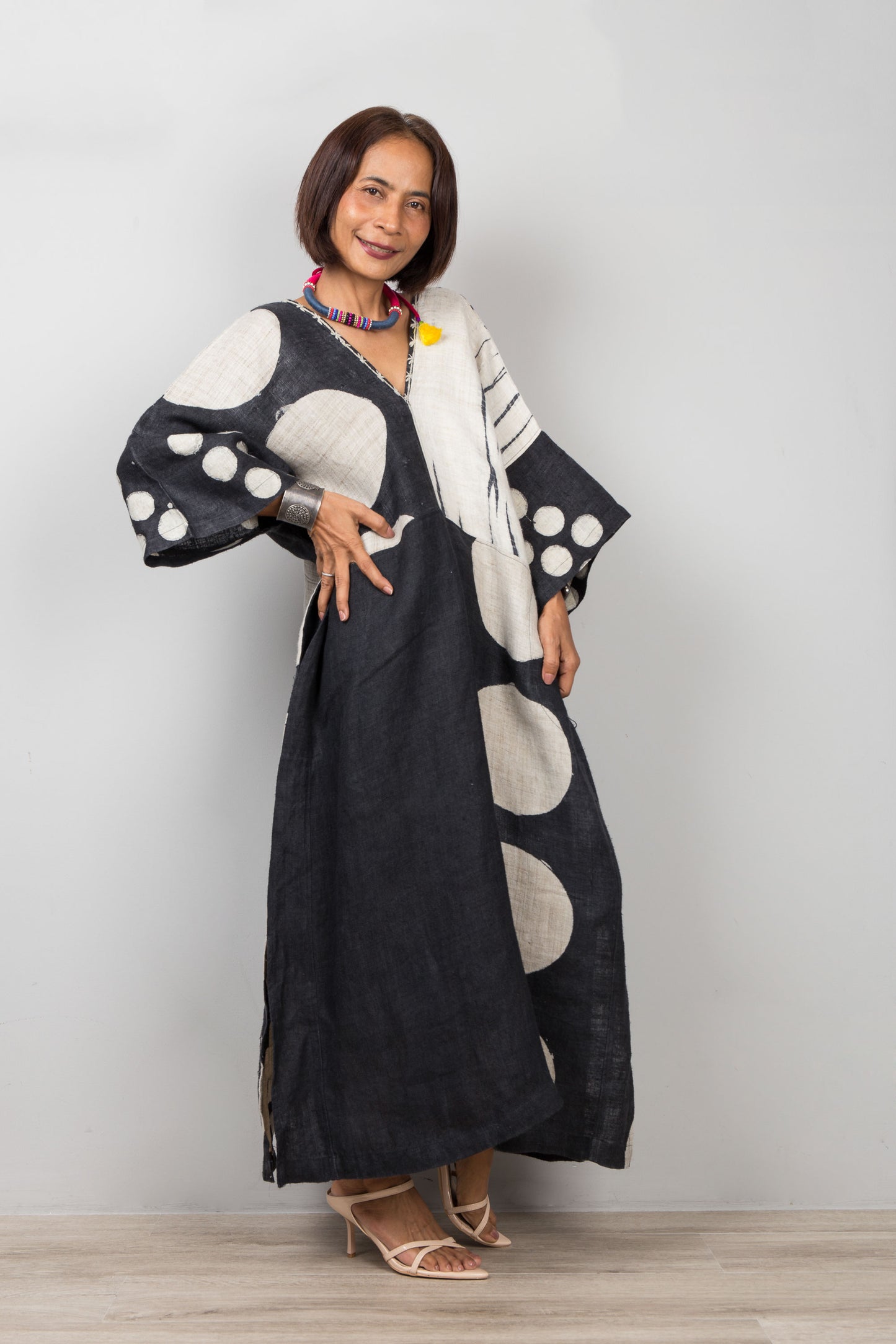 Nuichan wearing a black and white patterned, patchwork hemp kaftan dress against a plain background