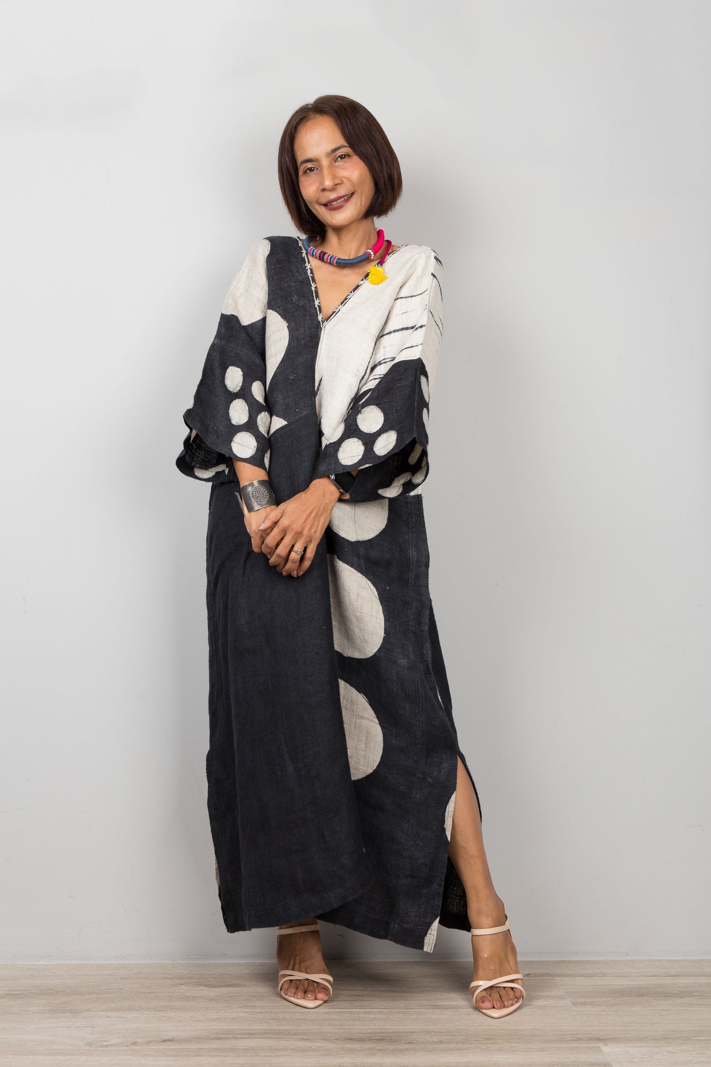 Woman wearing a long, dark-colored dress with white patterns against a plain background