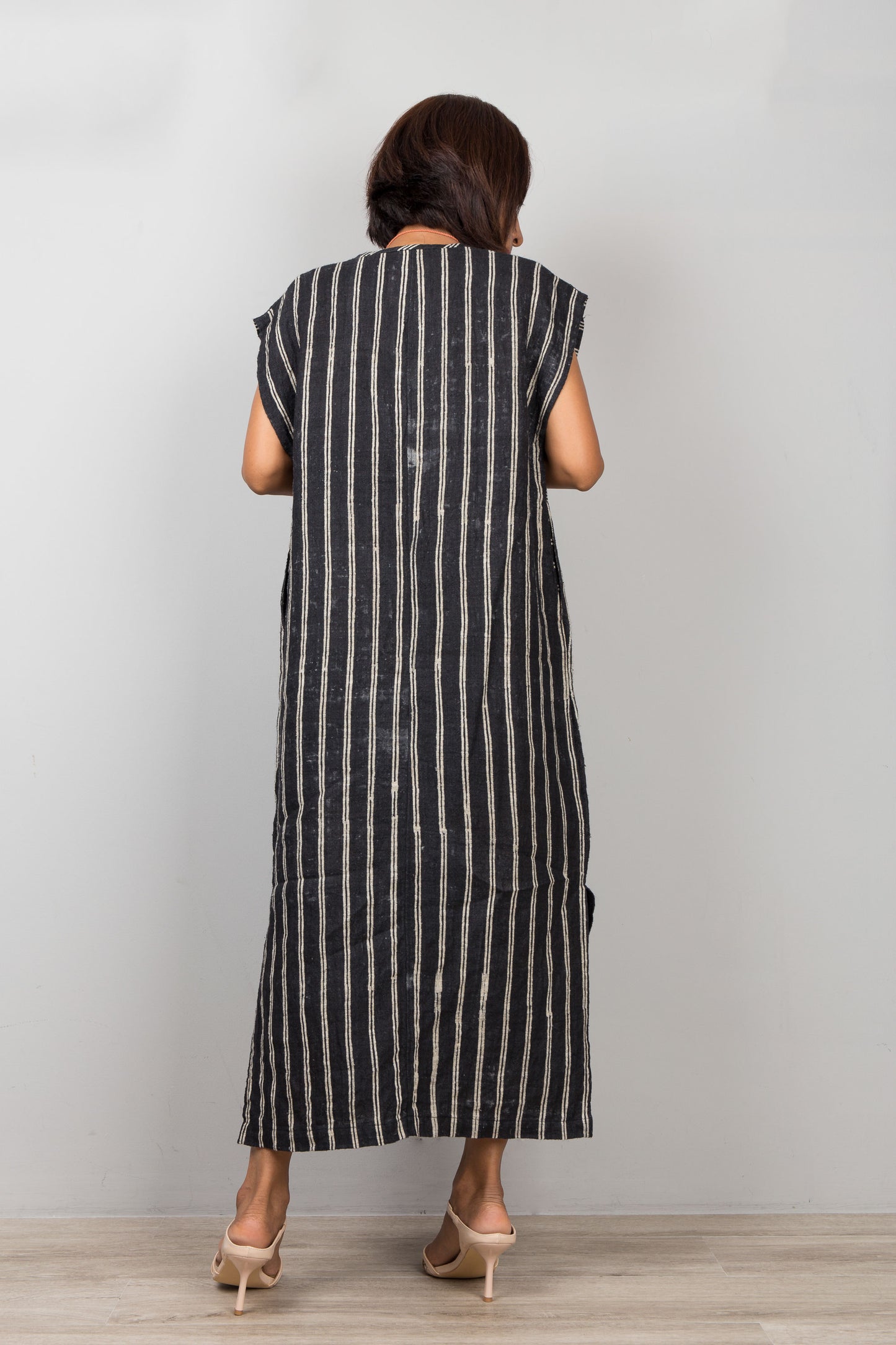 Woman wearing a black and white striped hemp dress against a plain background