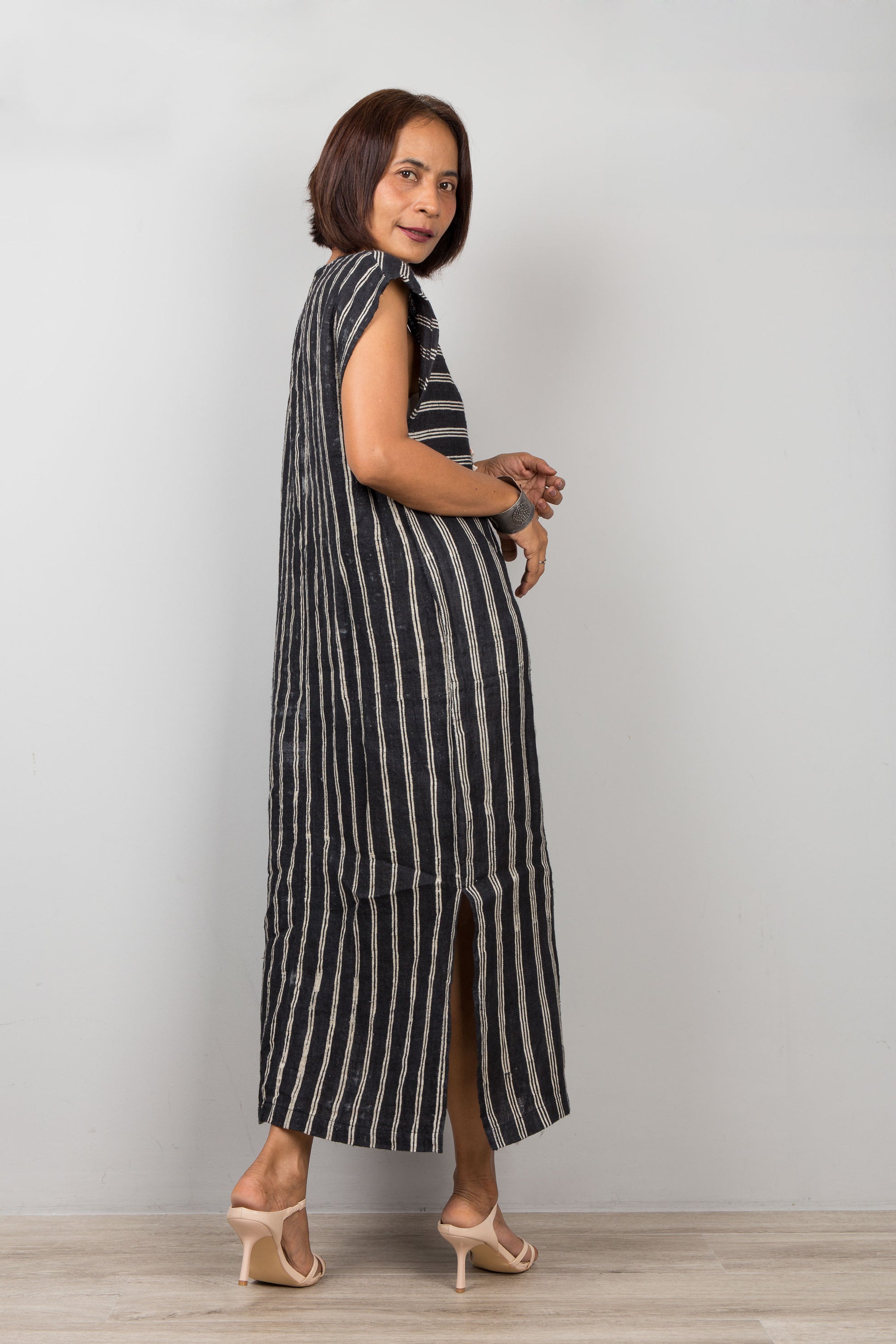 Woman wearing a black and white striped hemp dress with short sleeves against a plain background