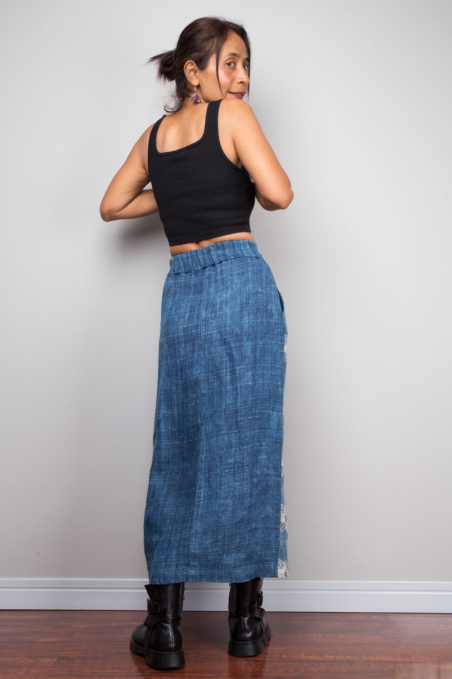 Back view of a model wearing the Nuichan indigo blue handwoven hemp wrap skirt, styled with a black crop top and ankle boots