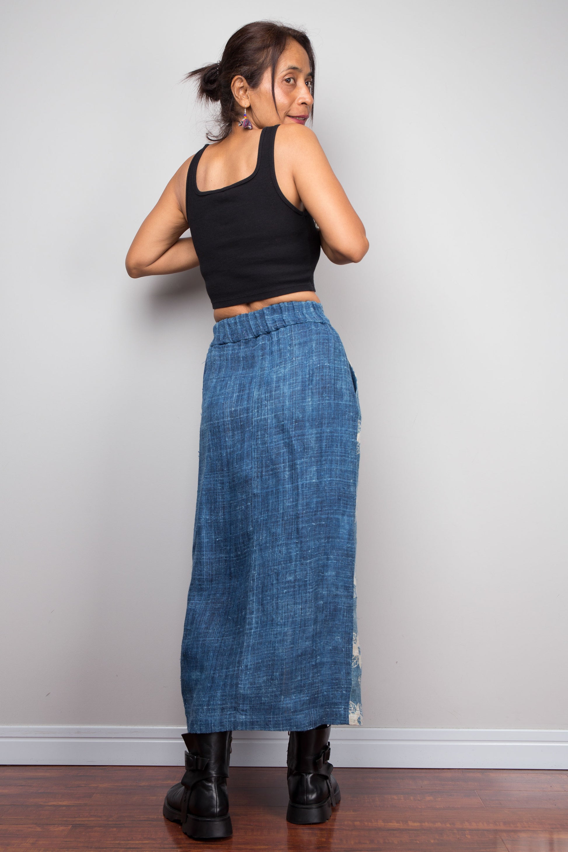 Back view of a model wearing the Nuichan indigo blue handwoven hemp wrap skirt, styled with a black crop top and ankle boots