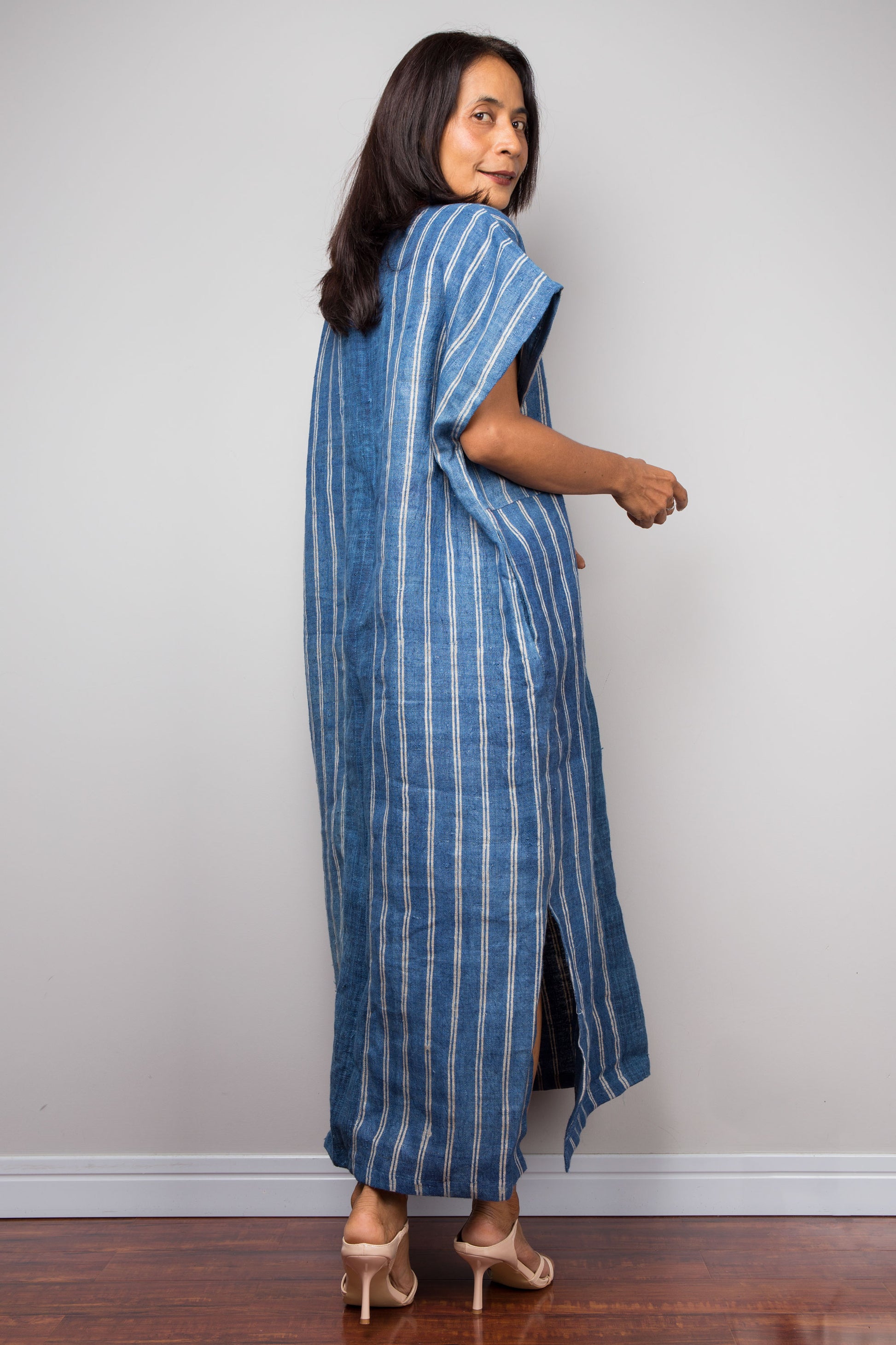 Woman wearing a blue and white striped dress against a plain background.  Hemp kaftan by Nuichan