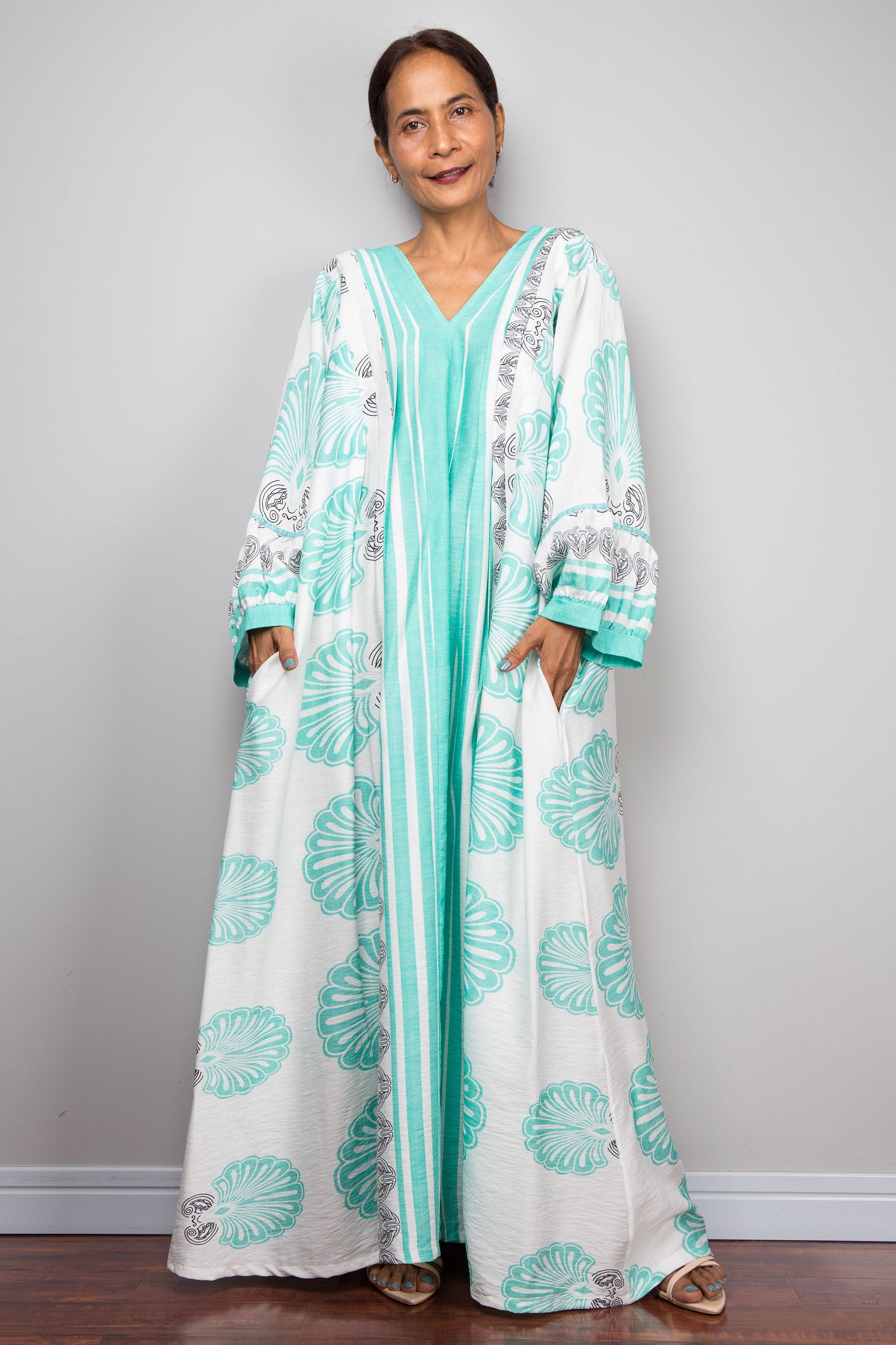 Full-length studio frontal shot of a model wearing the Nuichan bohemian caftan dress in mint green and white, highlighting the vertical-striped paneling, V-neckline,and functional side pockets.