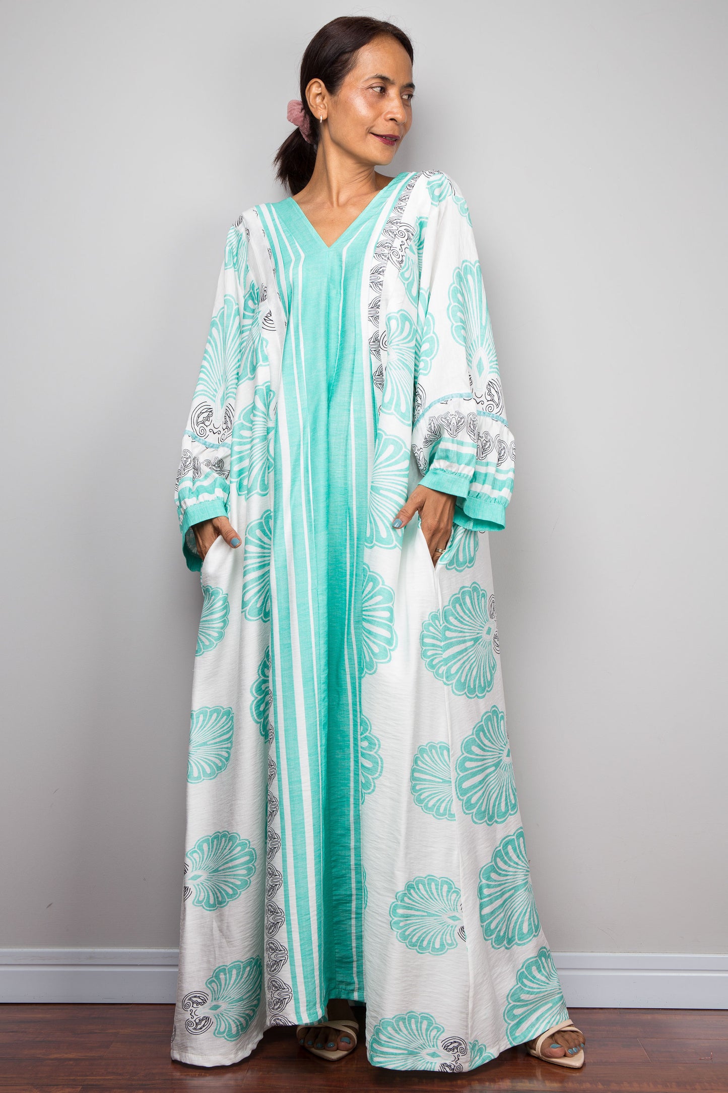 Frontal shot of a model wearing the Nuichan bohemian caftan dress in mint green and white, highlighting the vertical-striped paneling, V-neckline,and functional side pockets.