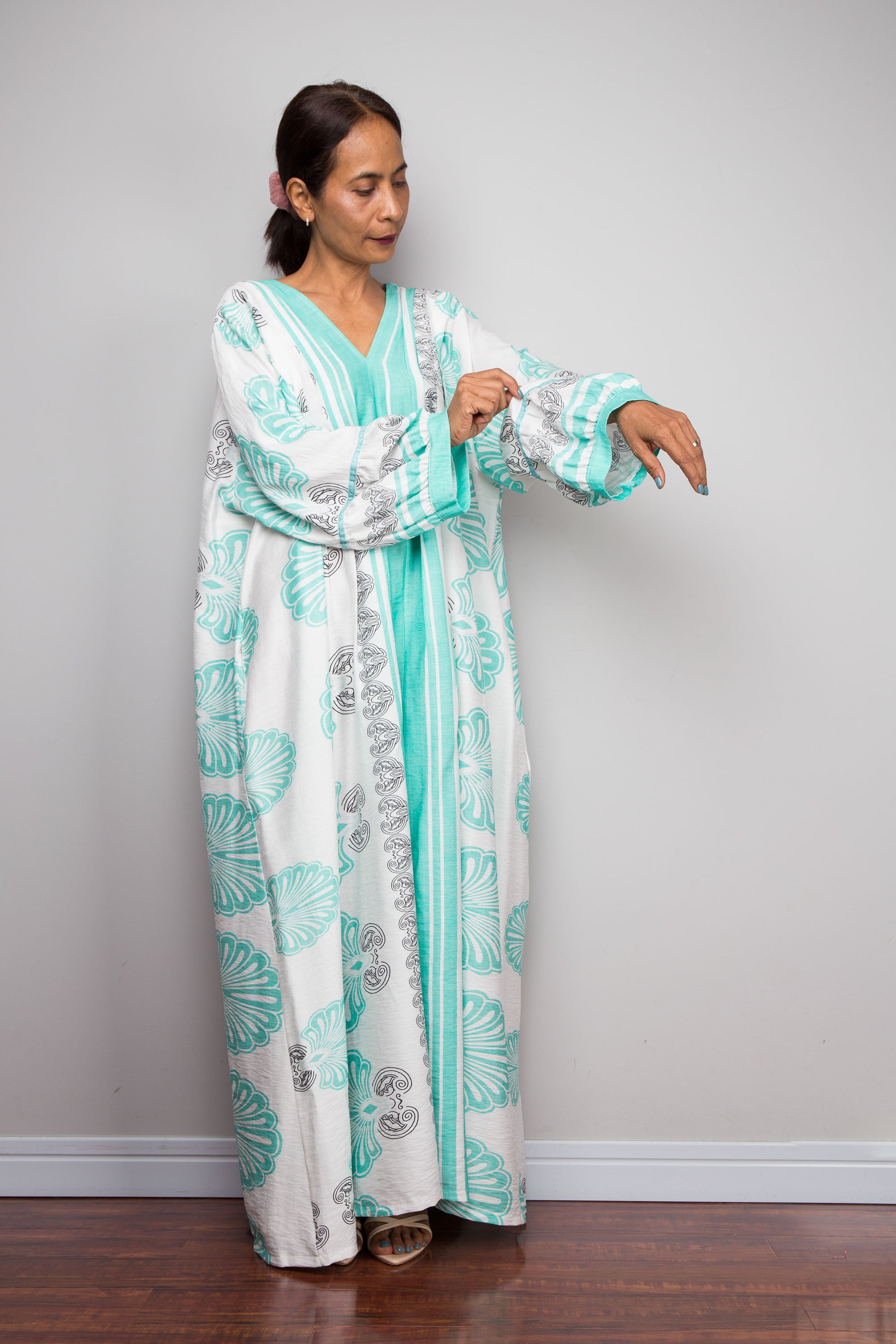 Full-length studio shot of a model wearing the Nuichan bohemian caftan dress in mint green and white, highlighting the vertical-striped paneling, V-neckline, and long billowy sleeves