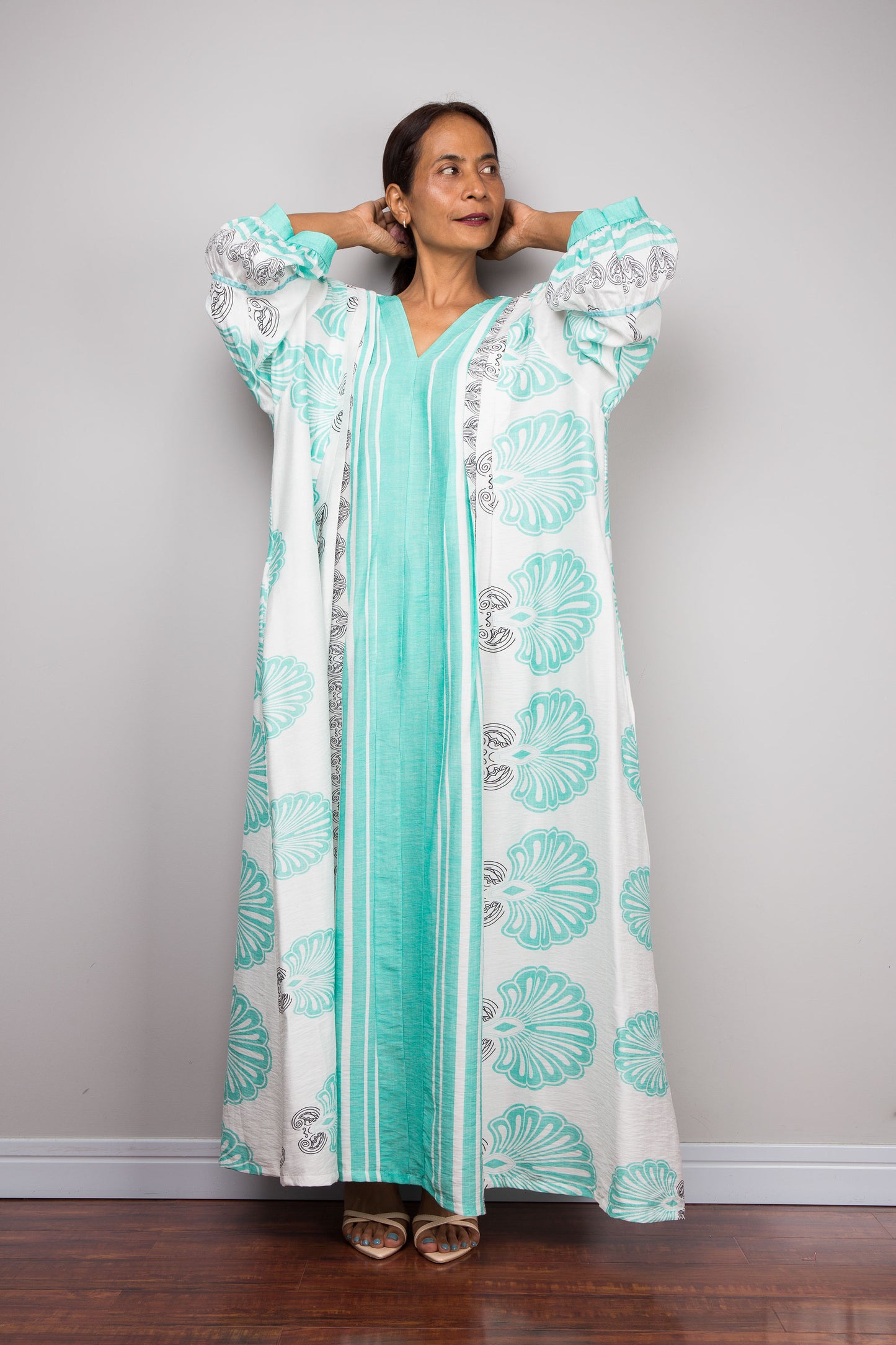 Full-length studio shot of a model wearing the Nuichan bohemian caftan dress in mint green and white, highlighting the vertical-striped paneling, V-neckline,and functional side pockets.