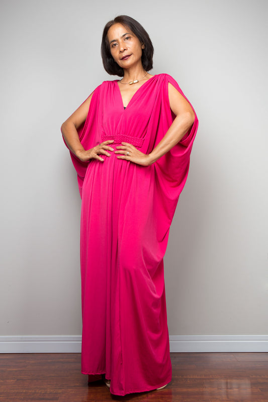 Woman wearing a hot pink caftan dress against a plain background