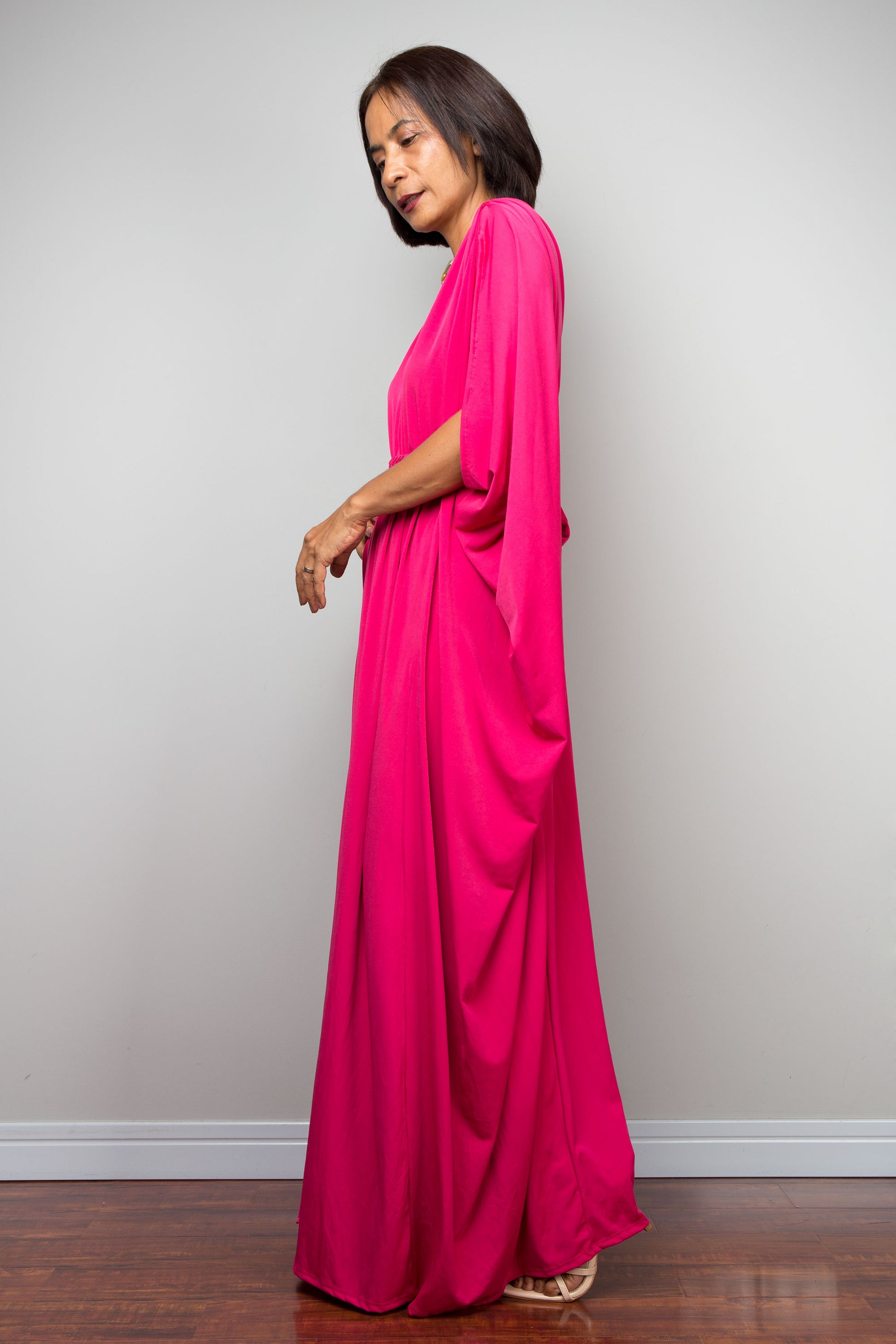 Petite woman wearing a hot pink caftan dress against a plain background