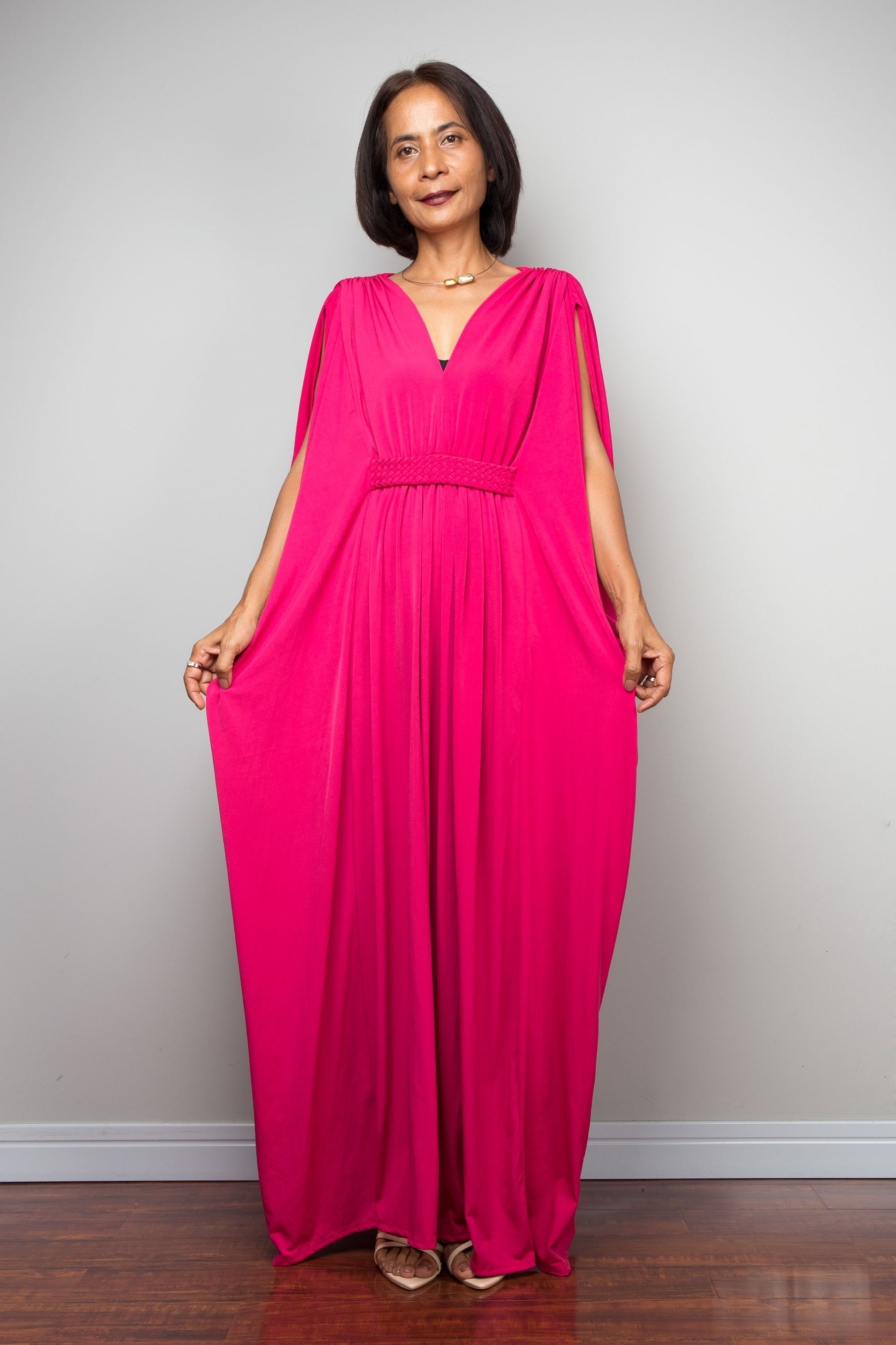 Petite woman wearing a bright pink dress against a plain background