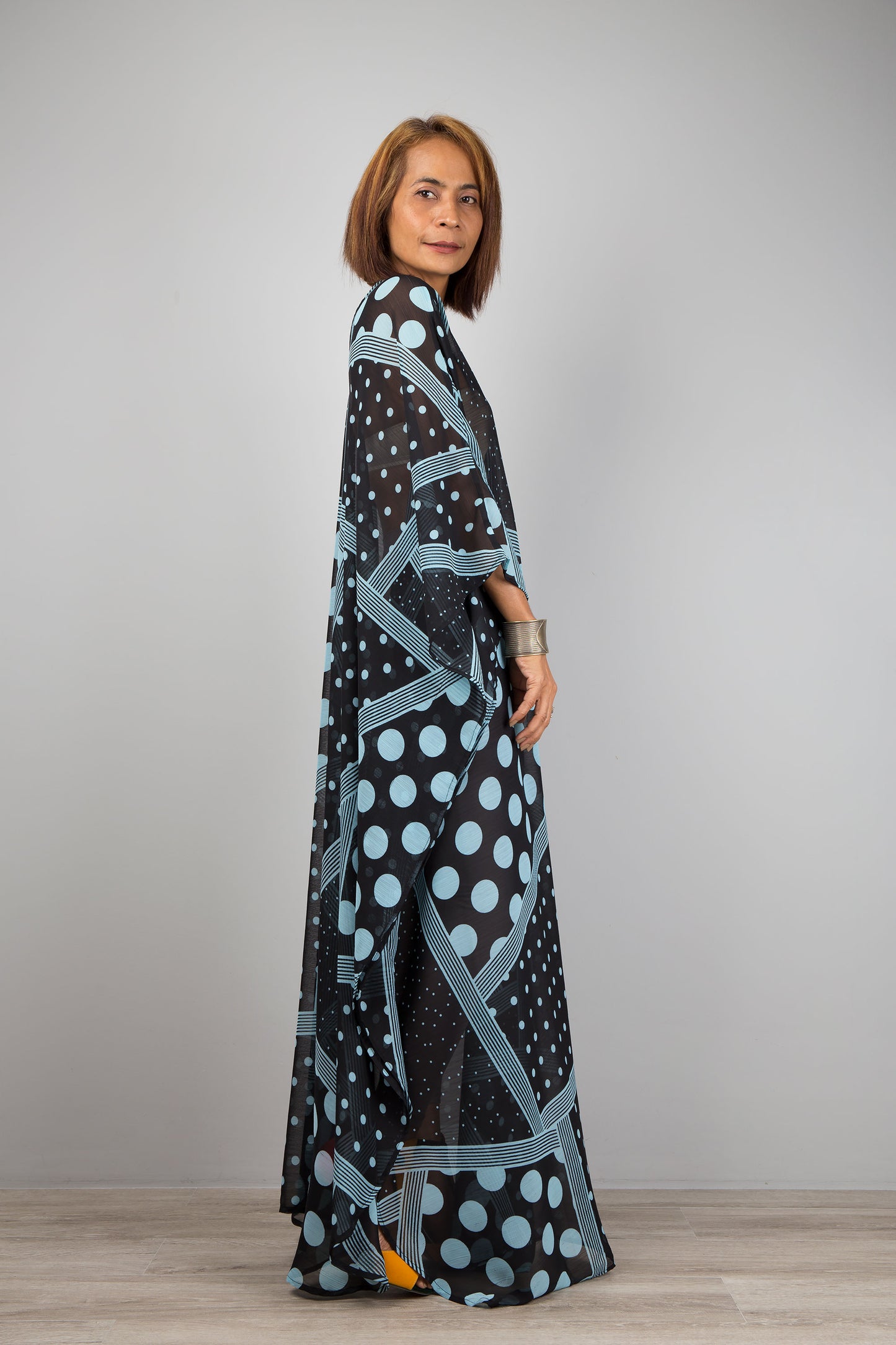 Light blue polka dot caftan dress by Nuichan.  Caftan with small v neck in a sheer chiffon fabric. Side view.