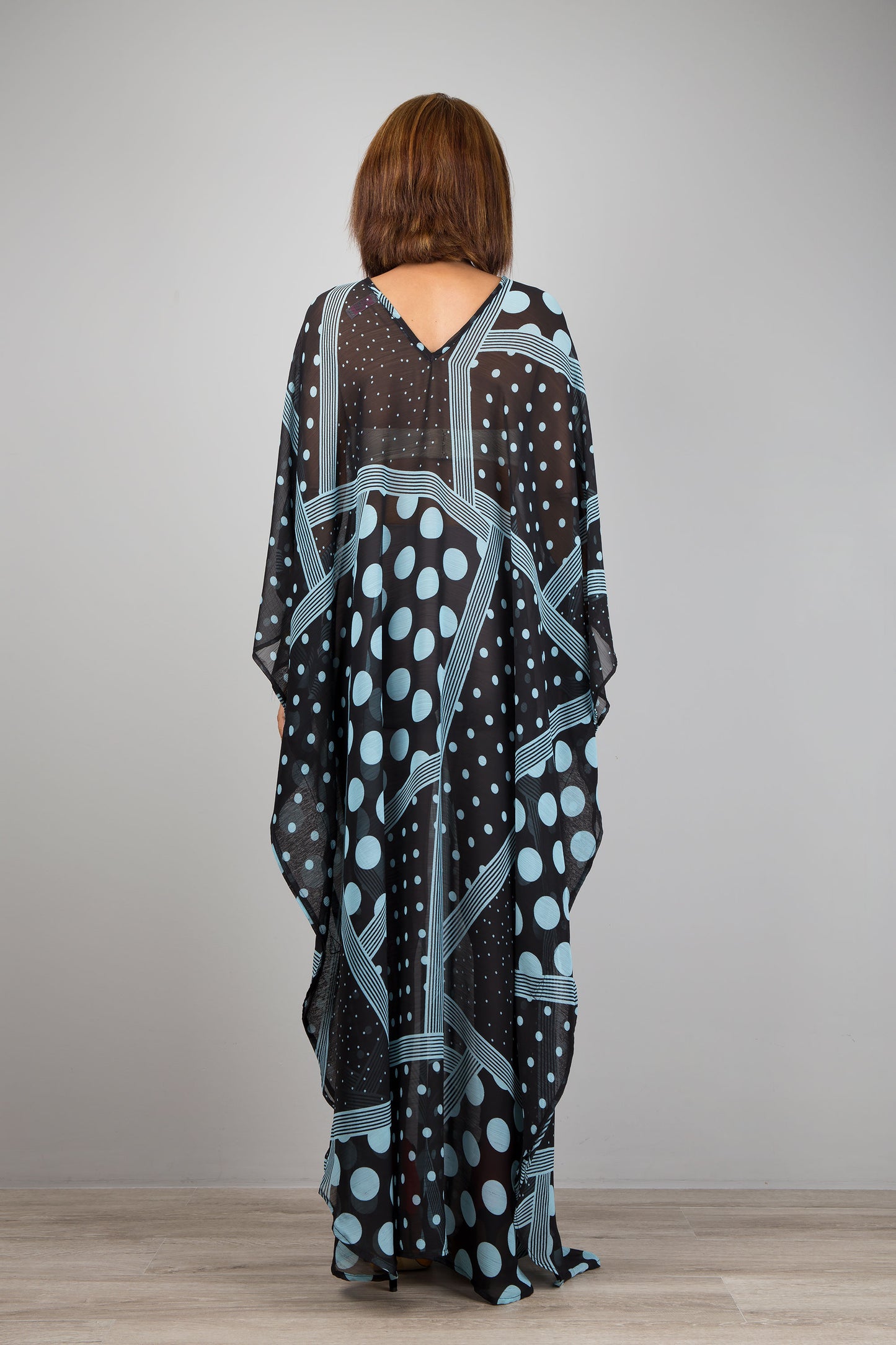 Light blue polka dot kaftan dress by Nuichan.  Caftan with small v neck in a sheer chiffon fabric. Back view