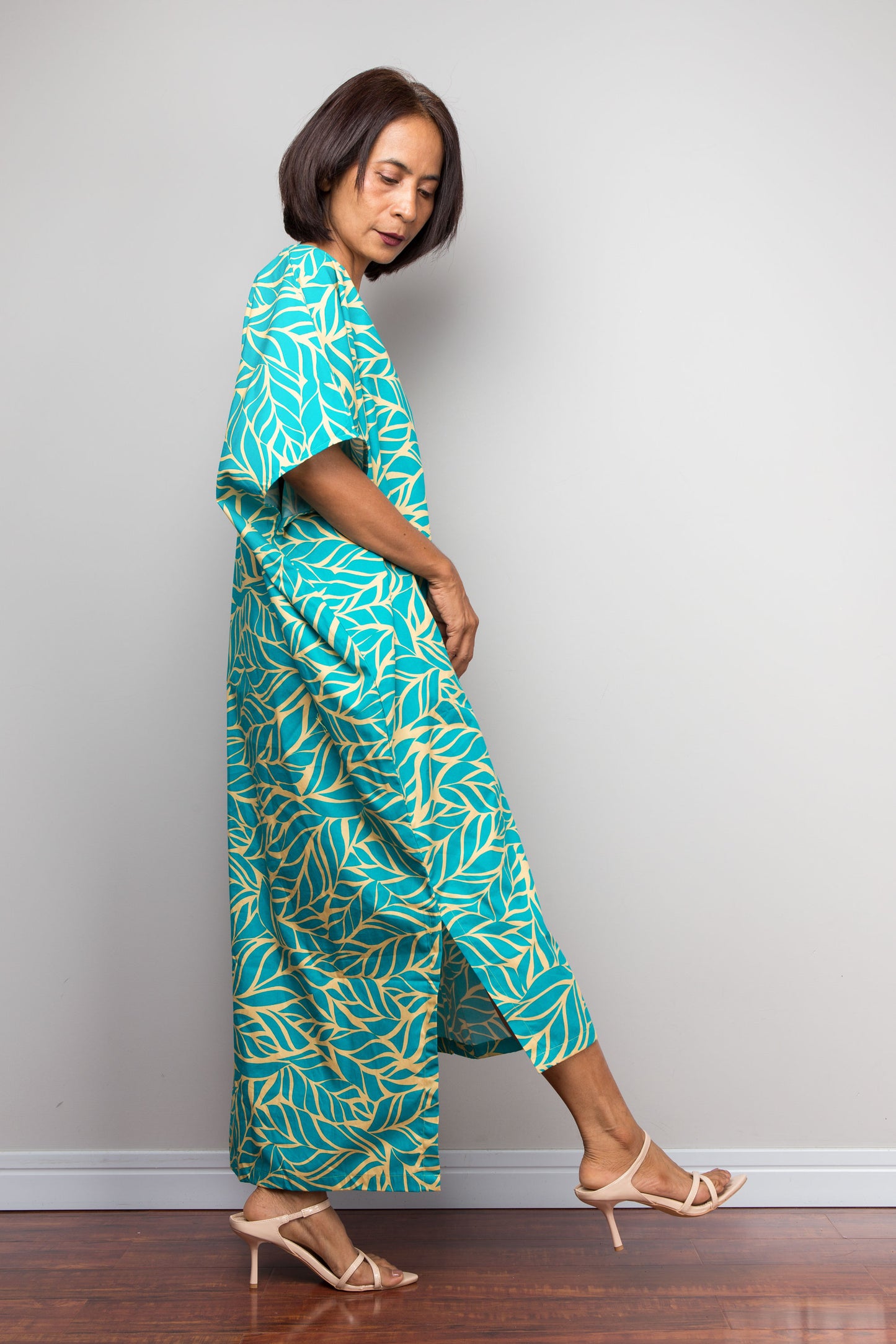 Woman wearing a teal and yellow patterned outfit against a plain background