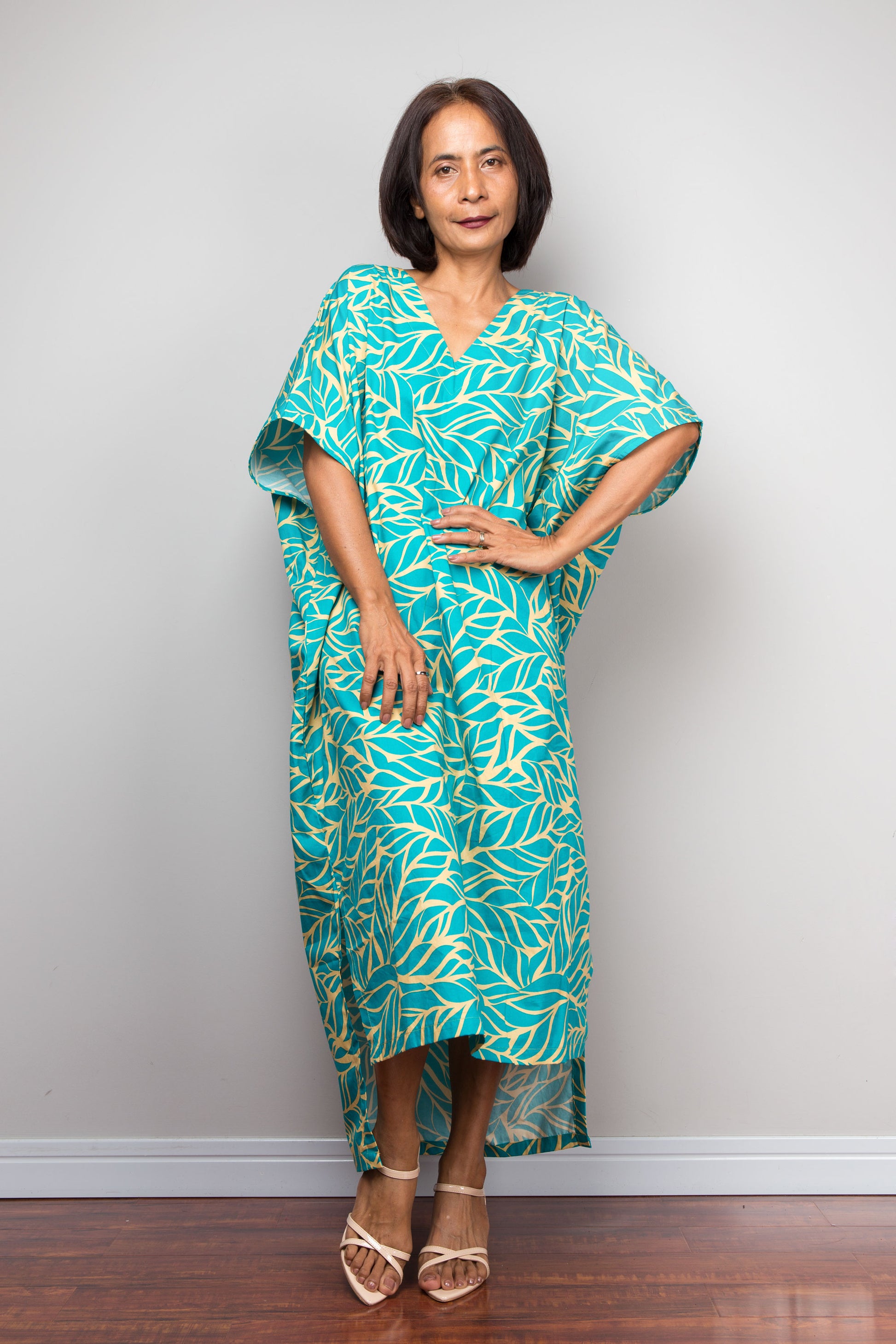 Woman wearing a teal and yellow patterned caftan dress for petite against a plain background