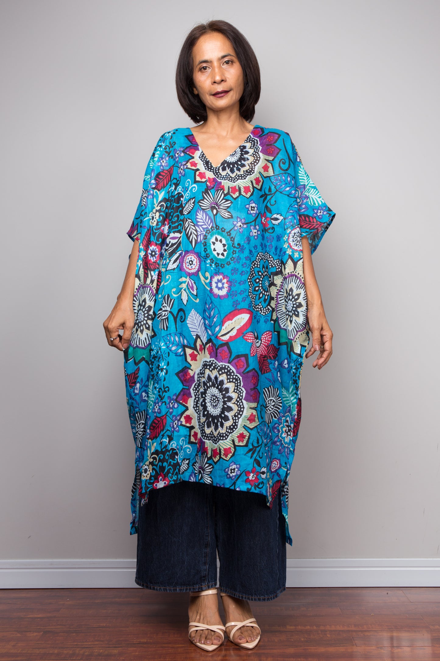 Woman wearing a colorful patterned cotton caftan dress against a plain background