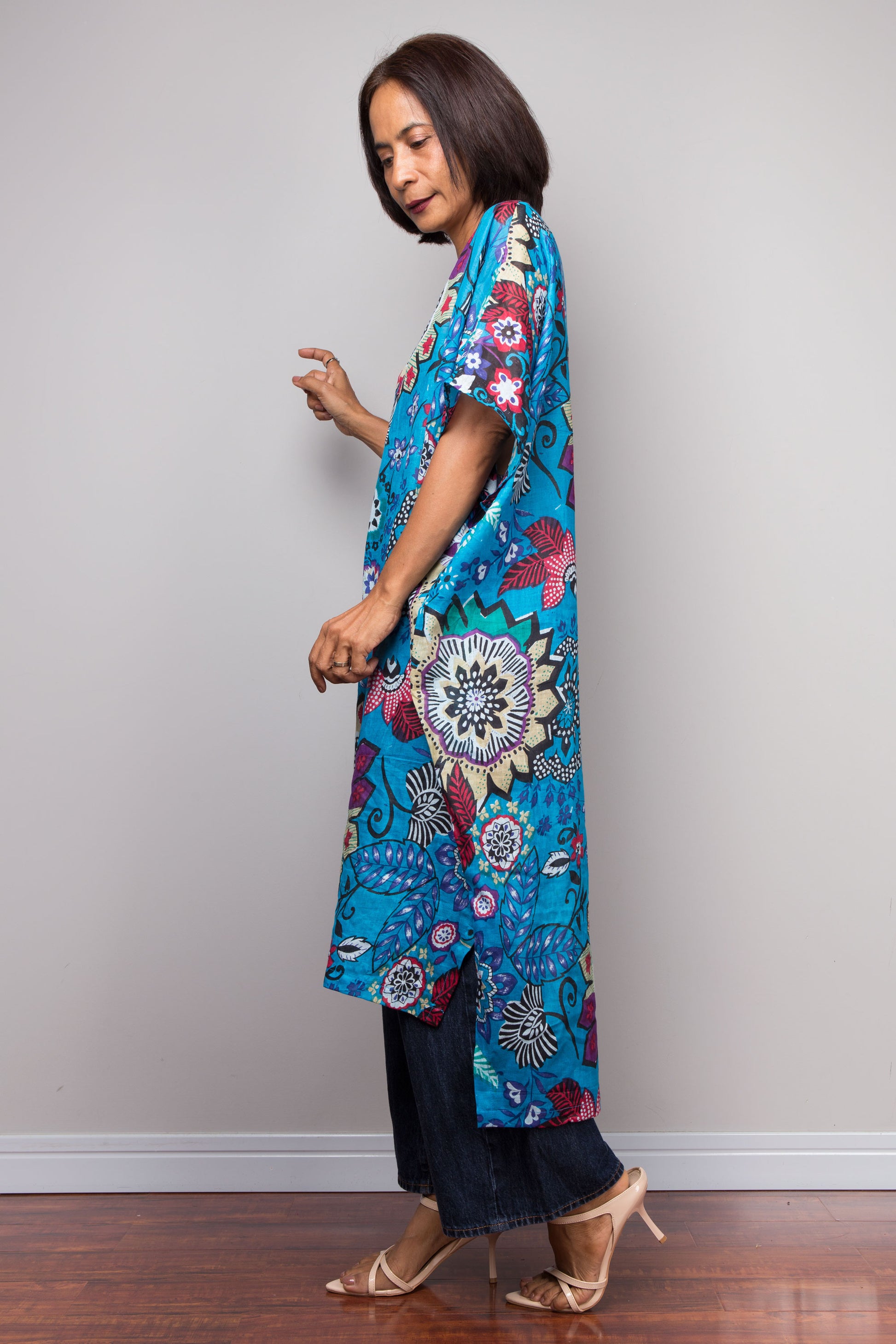 Woman wearing a colorful blue floral cotton caftan dress against a plain background