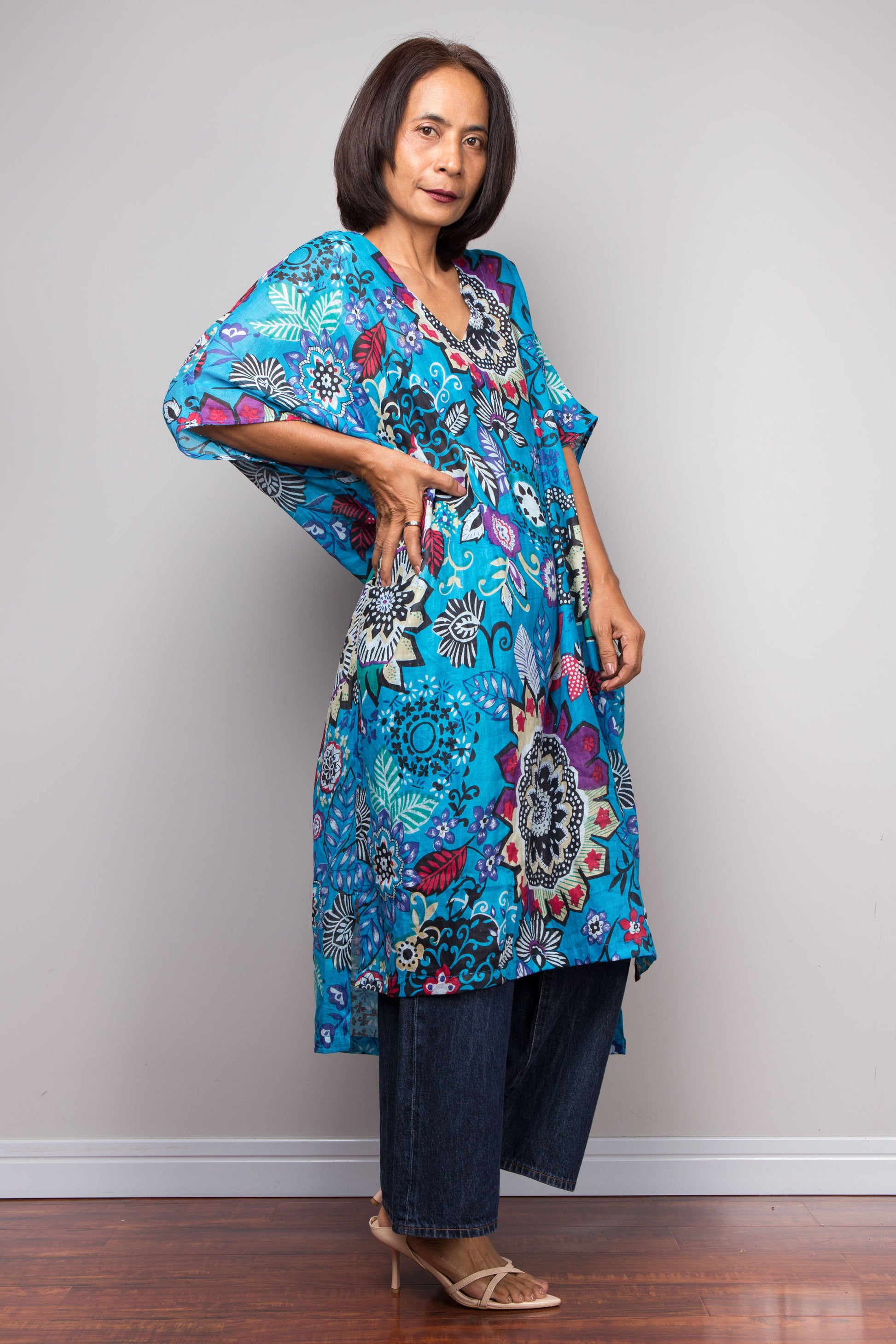 Woman wearing a colorful floral caftan garment against a plain background