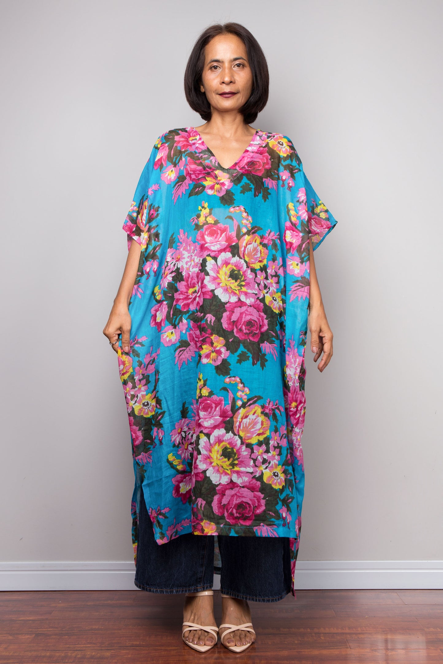 Petite Woman wearing a colorful floral caftan against a plain background