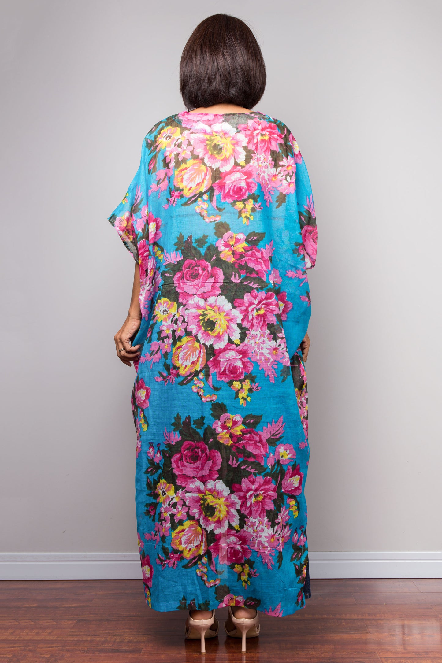 Petite Woman wearing a colourful floral caftan dress against a plain background
