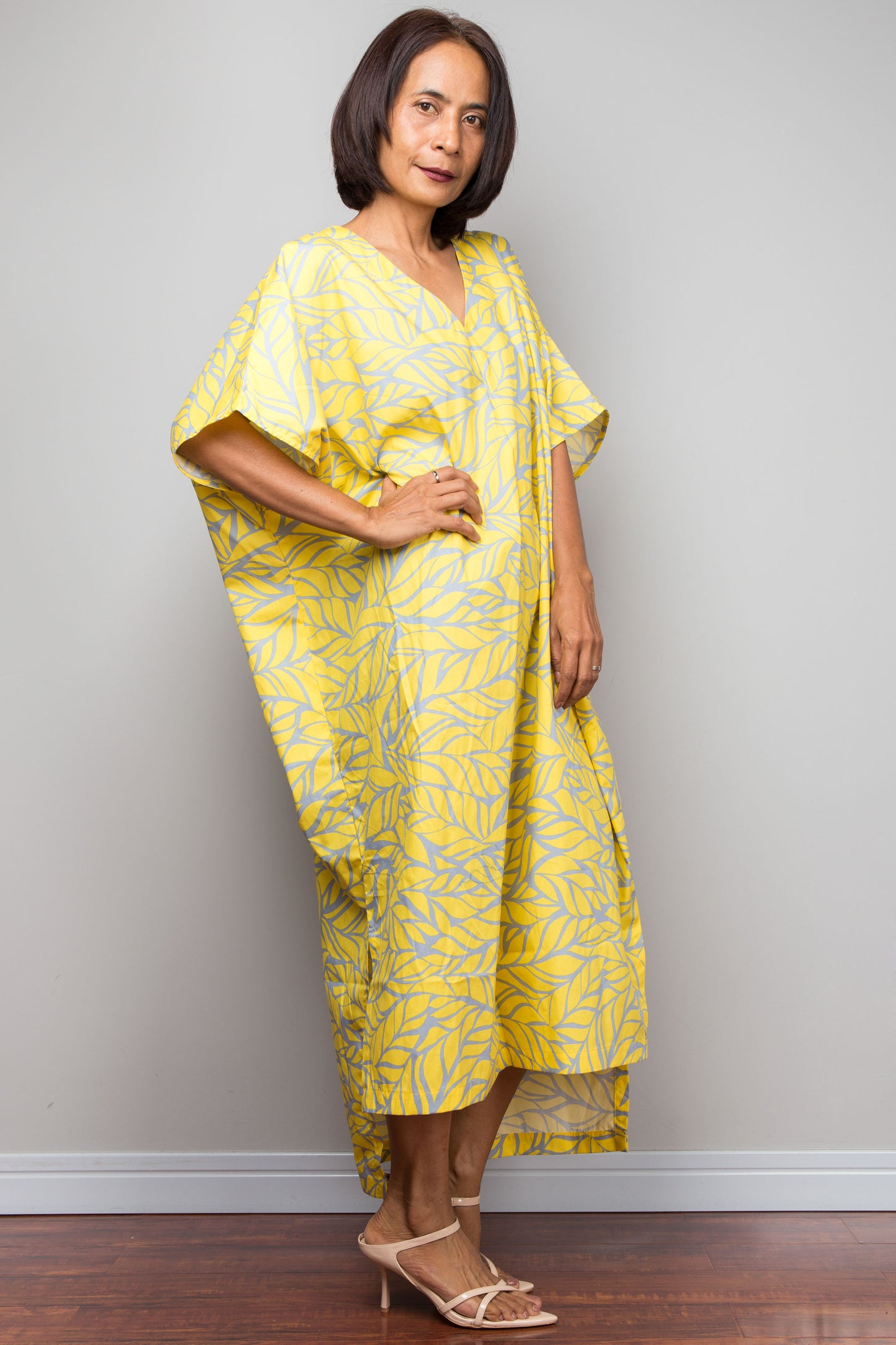 Petite Woman wearing a yellow patterned dress against a plain background