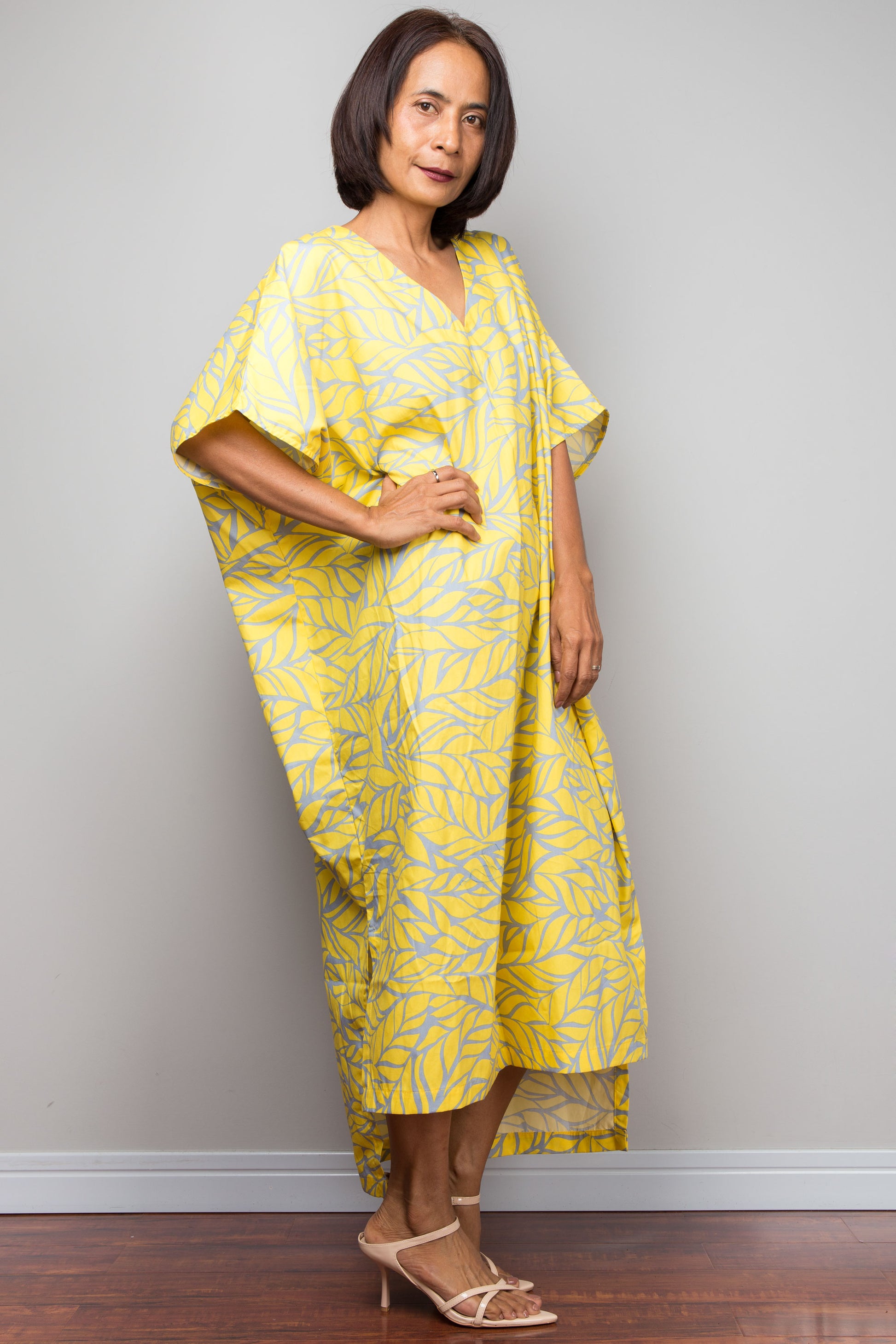 Petite Woman wearing a yellow patterned dress against a plain background