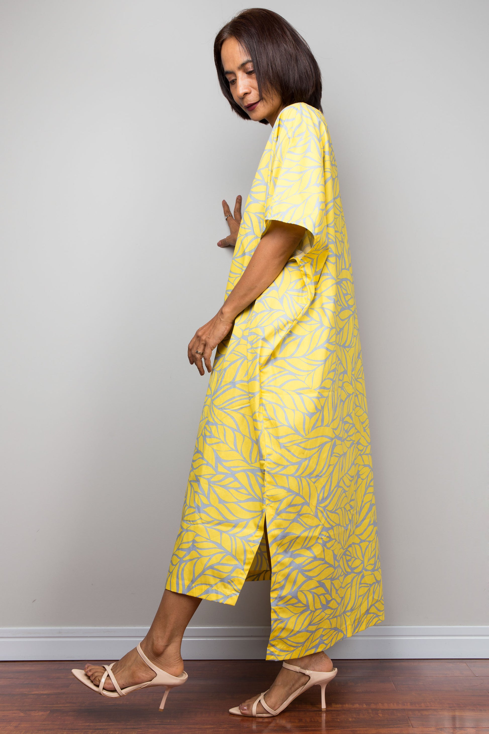 Woman wearing a yellow patterned cotton maxi kaftan dress against a plain background