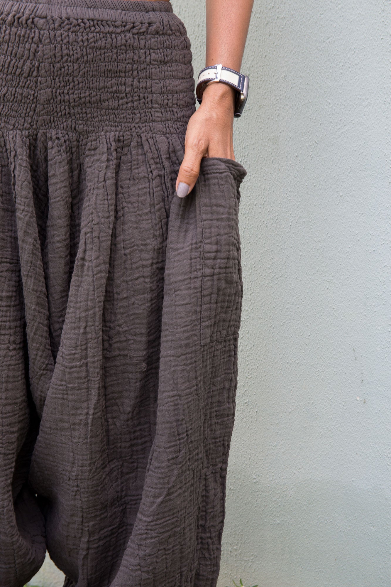 Person wearing a charcoal grey textured cotton gauze harem pants against a light gray background