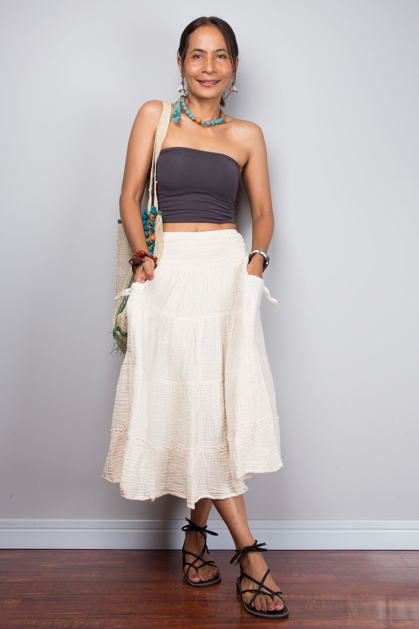 Woman wearing a purple top and white cotton skirt against a plain background