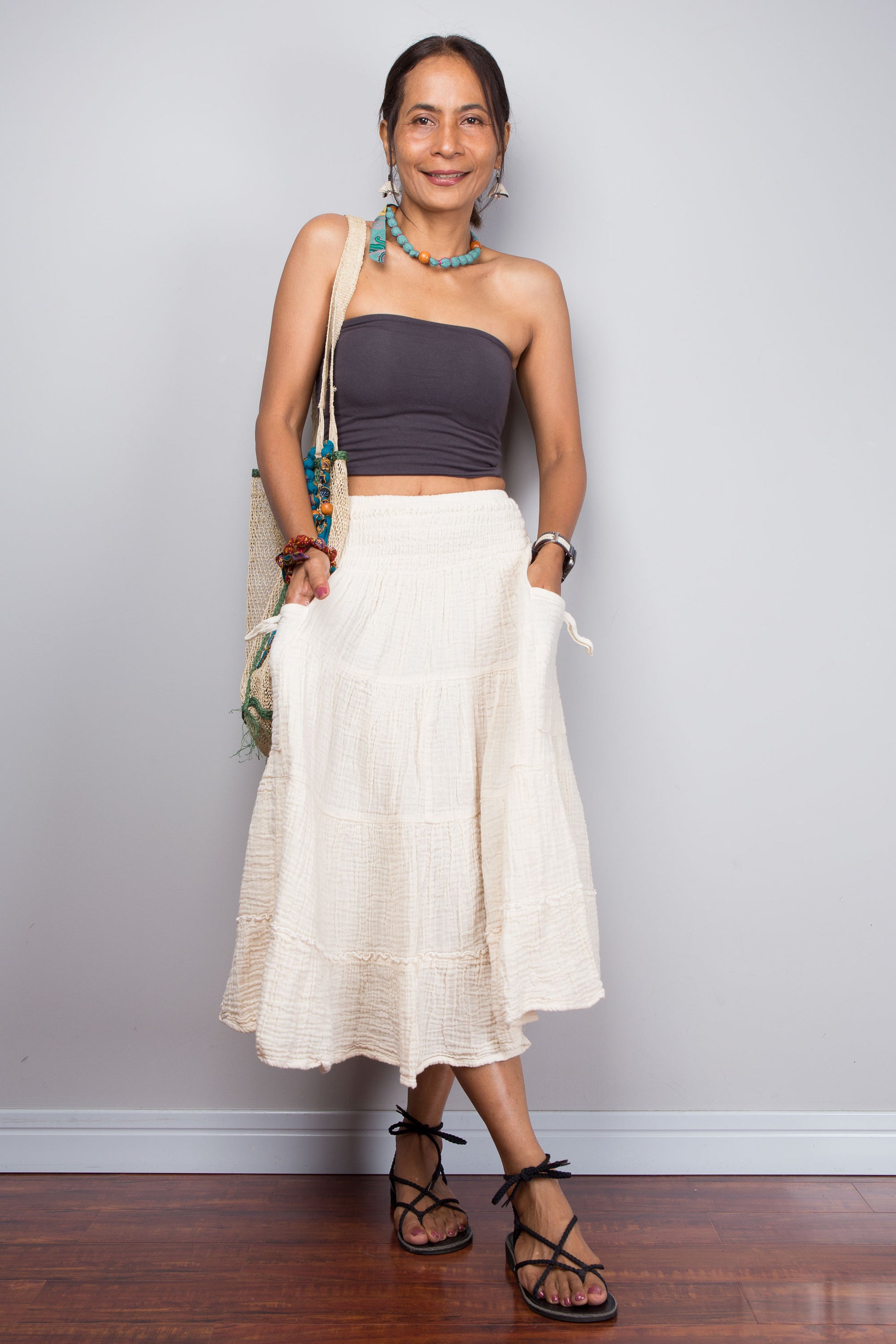 Woman wearing a purple top and white cotton skirt against a plain background
