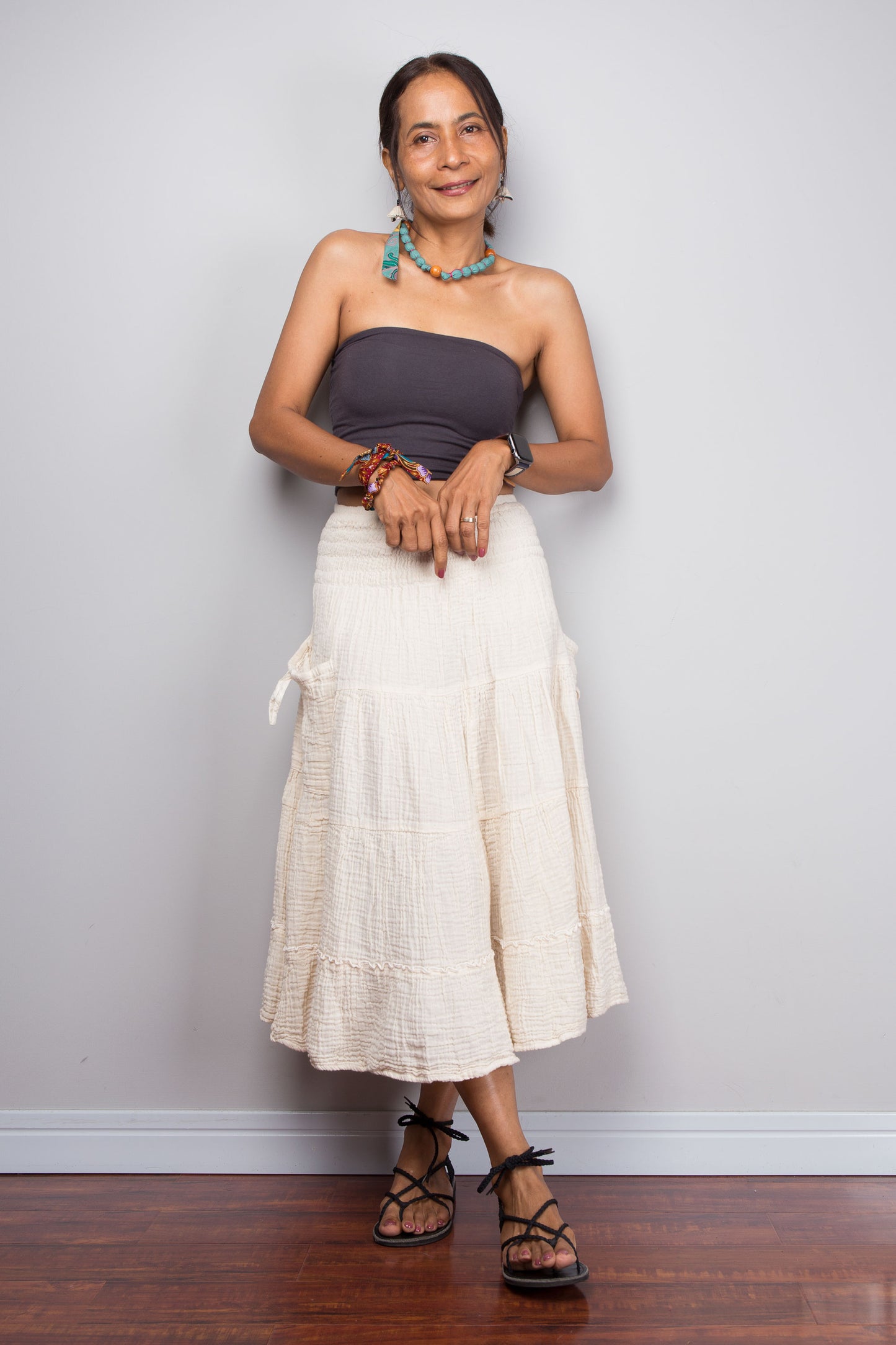 Woman wearing a strapless top and white skirt against a plain background