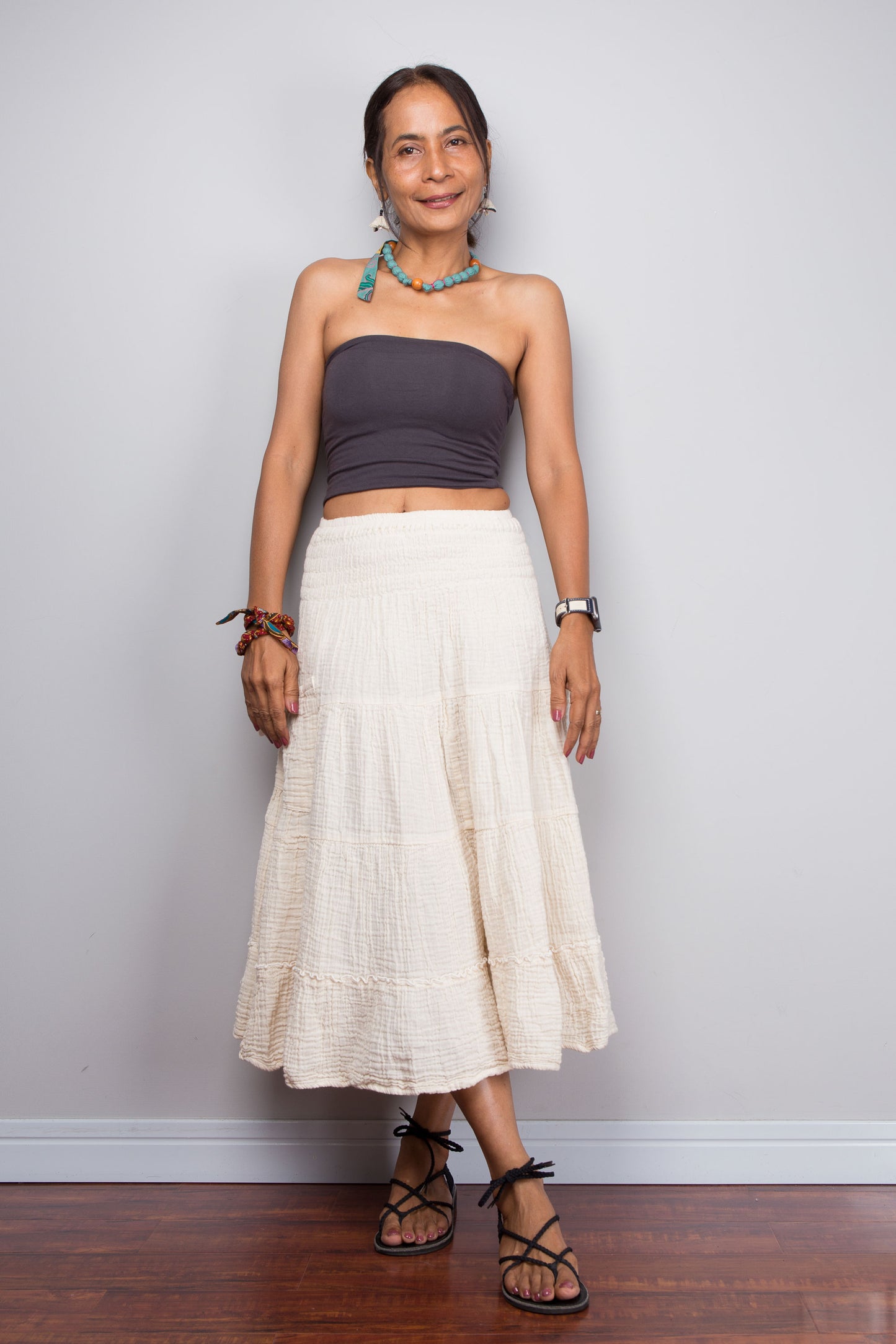 Woman wearing a strapless top and white skirt against a plain background