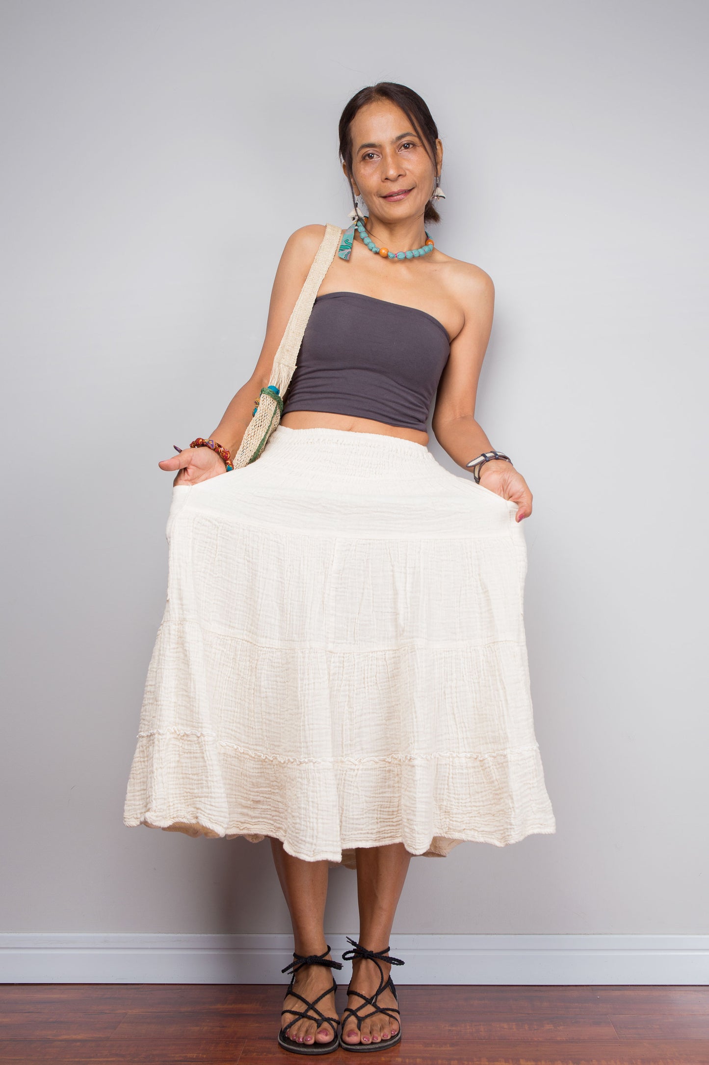 Woman wearing a strapless top and white skirt against a plain background