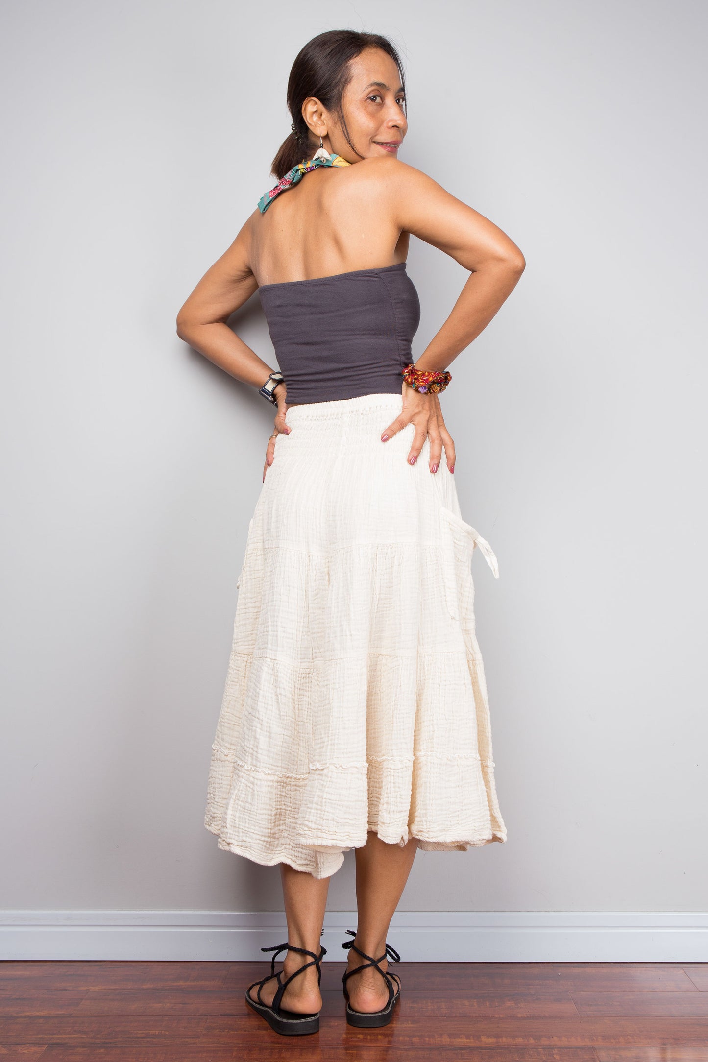 Woman wearing a strapless top and white skirt against a plain background