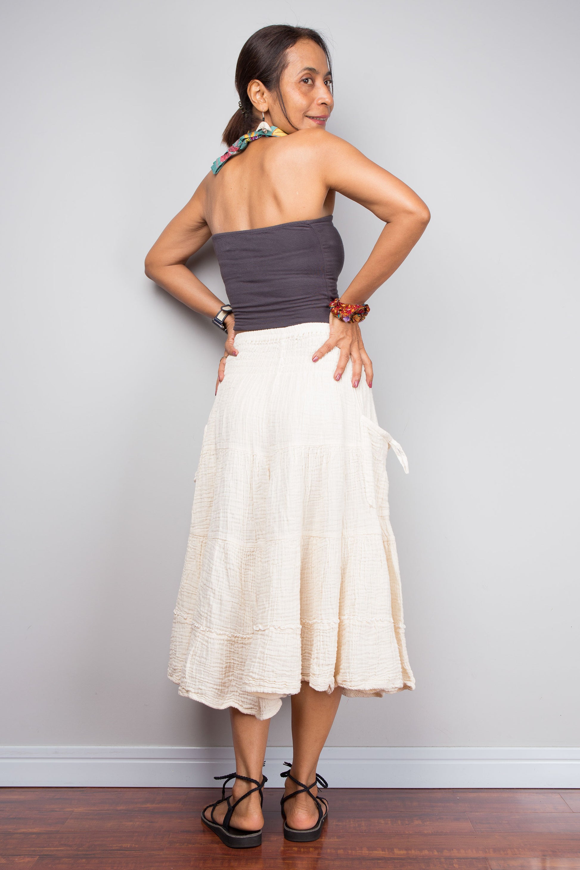 Woman wearing a strapless top and white skirt against a plain background