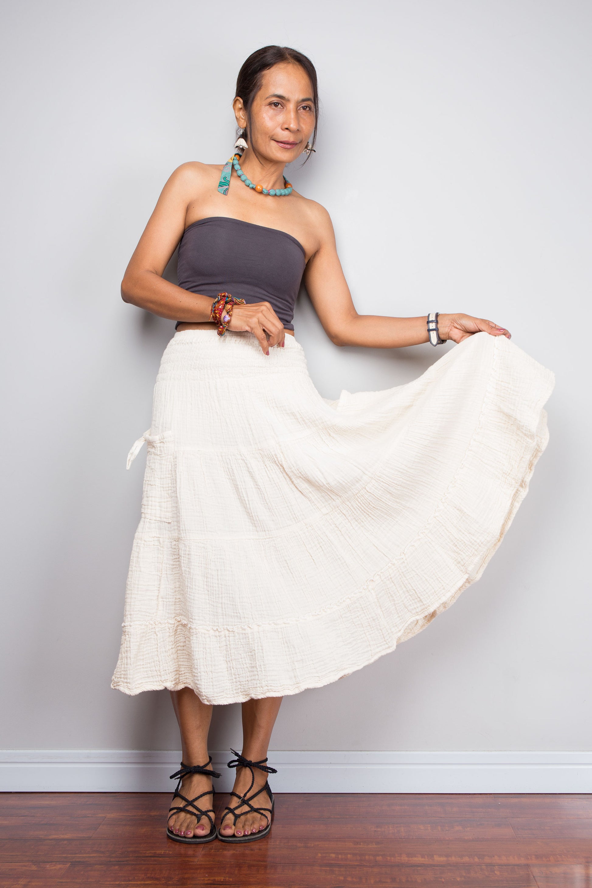 Woman wearing a white skirt and purple top against a plain background