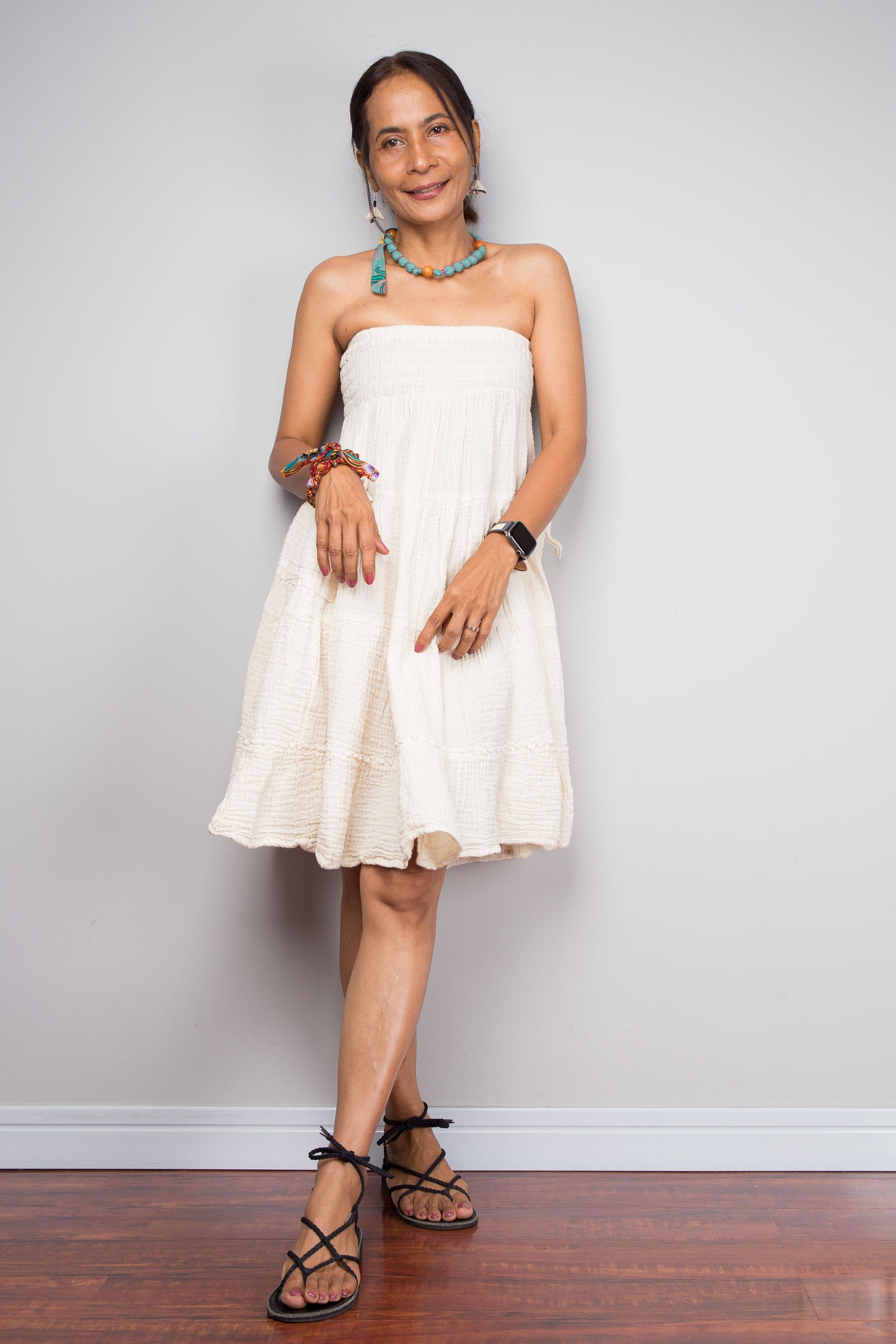 Woman wearing a white strapless cotton dress against a plain background