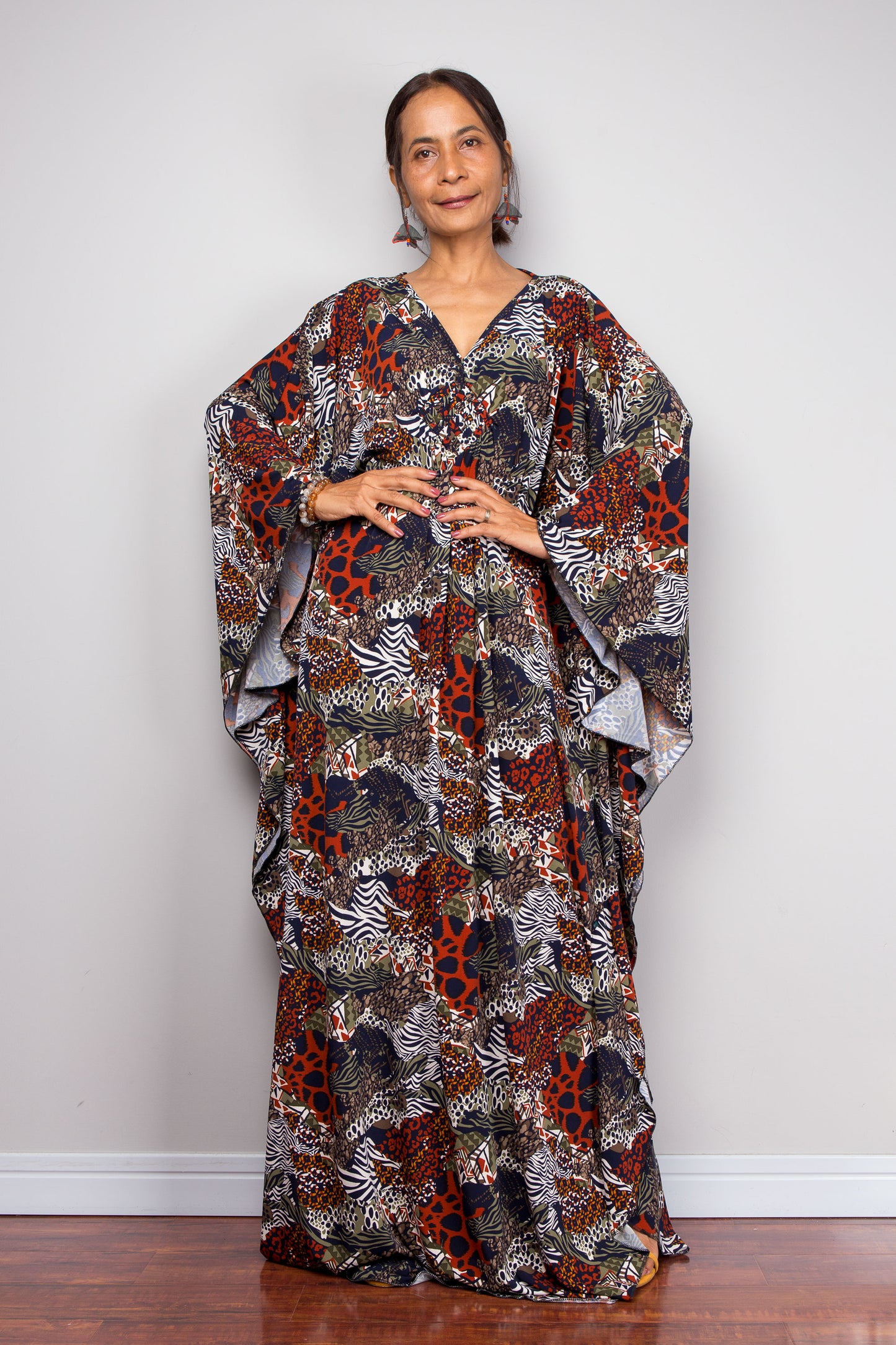 Woman wearing a floral patterned kaftan dress standing against a plain background