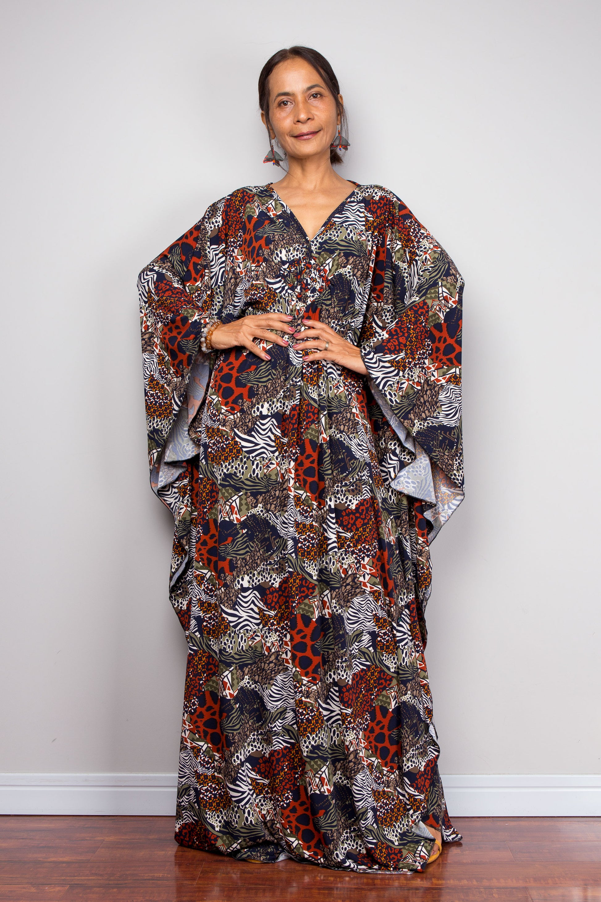 Woman wearing a floral patterned kaftan dress standing against a plain background