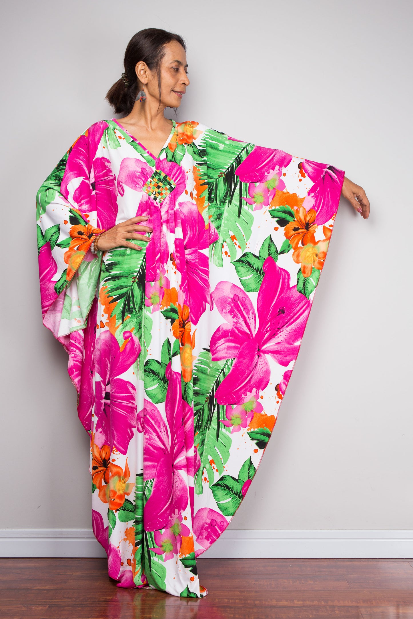 Woman wearing a colorful floral kaftan dress against a plain background