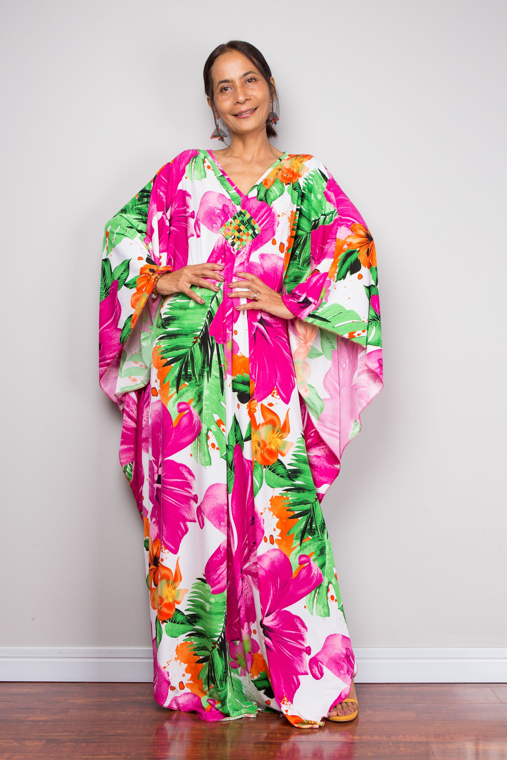 Woman wearing a colorful floral caftan dress with a white background
