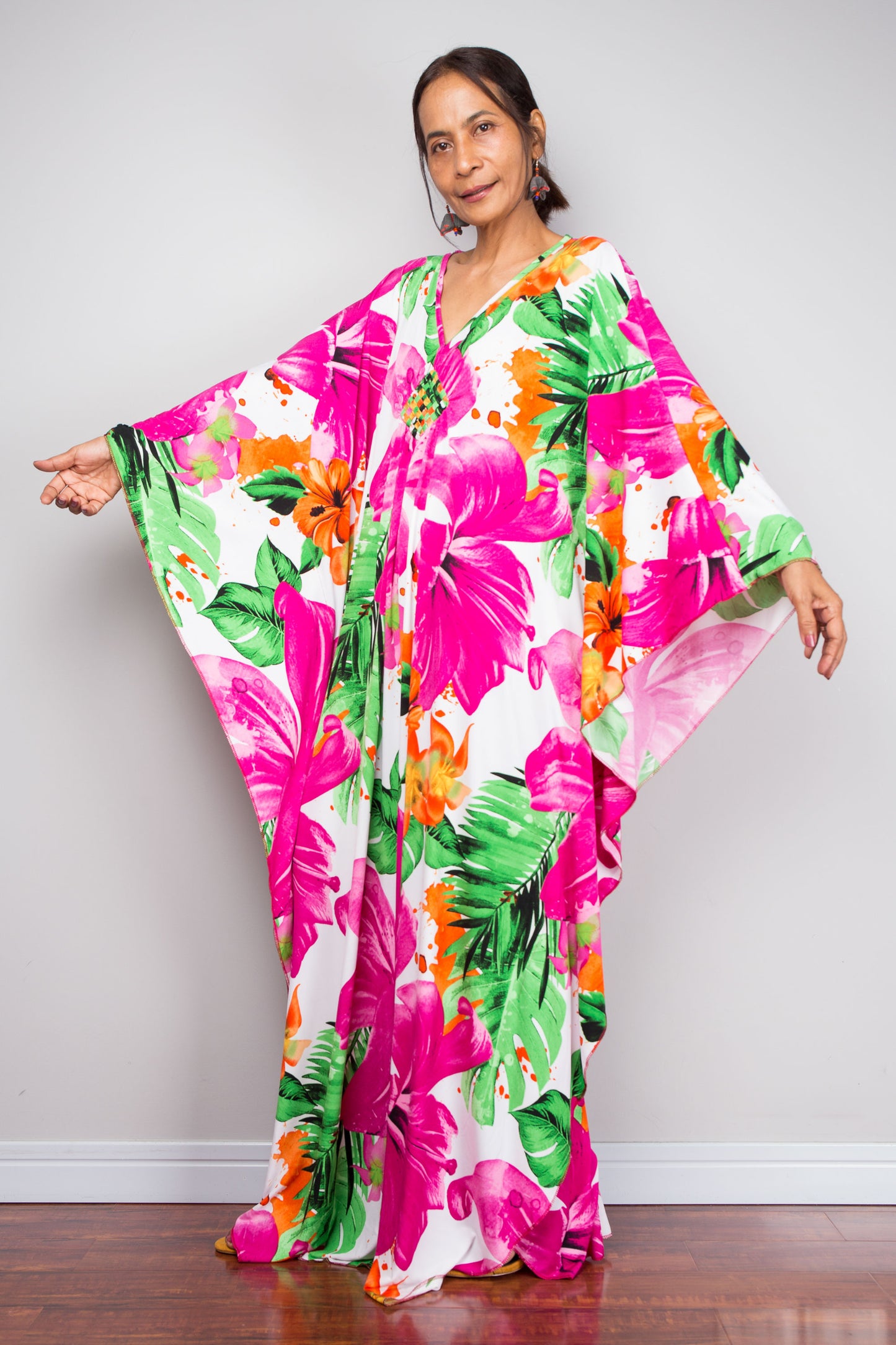 Woman wearing a colorful floral dress against a plain background