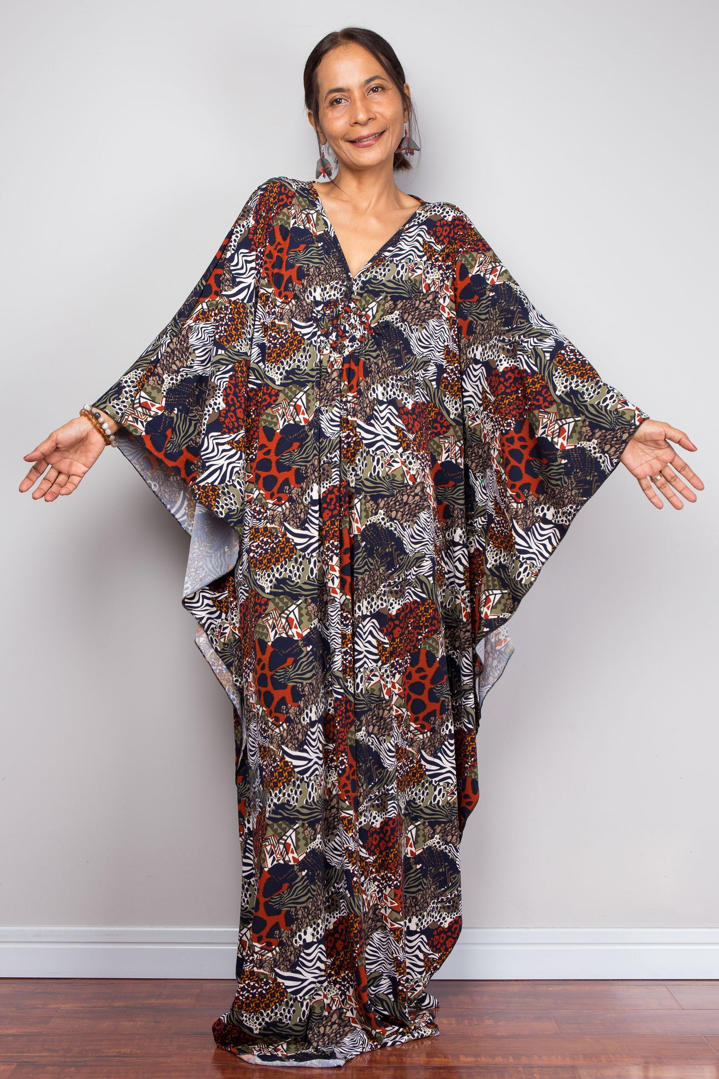 Woman wearing a patterned caftan against a plain background
