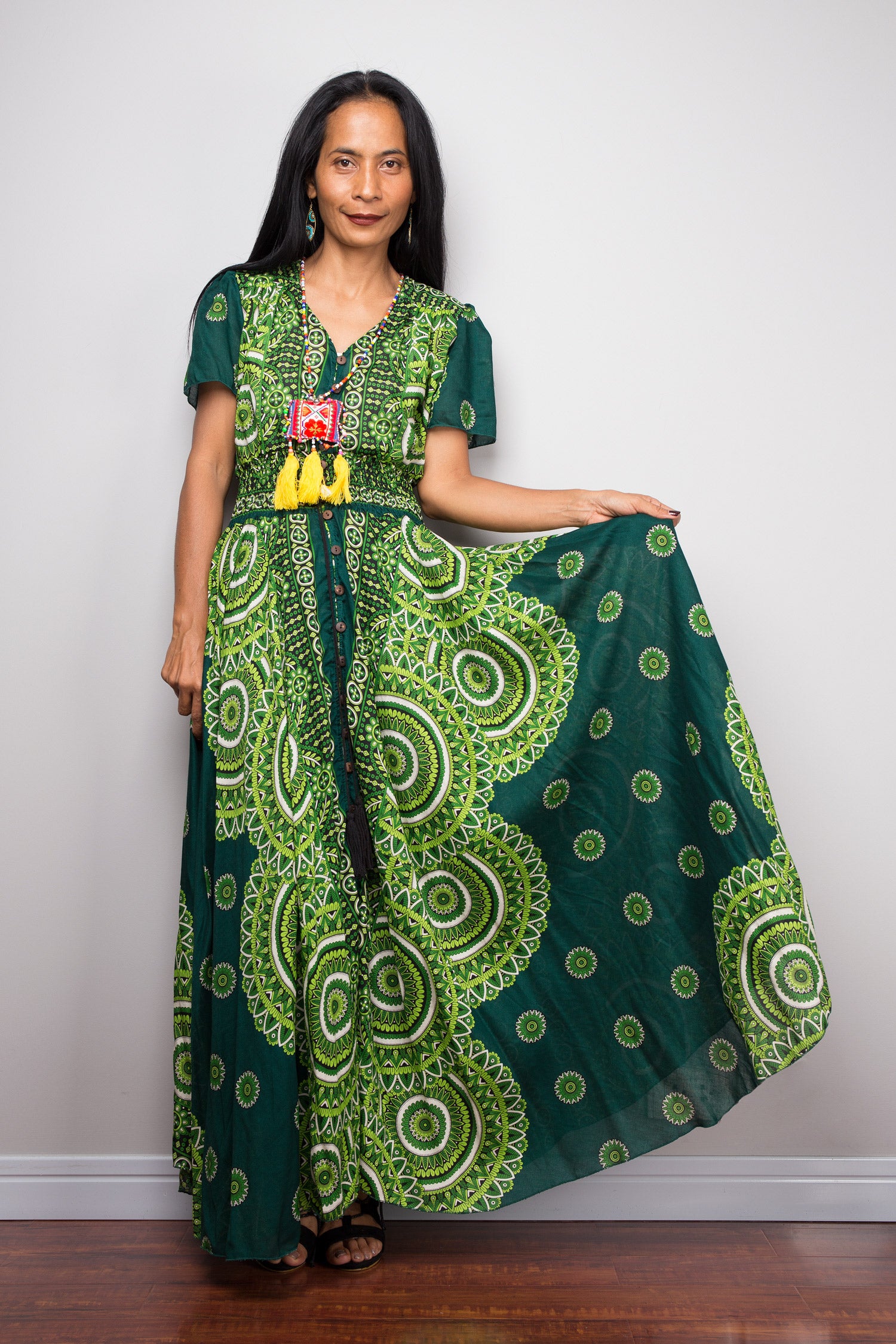 Woman wearing a green patterned dress holding another similar dress. Duster with buttons by Nuichan